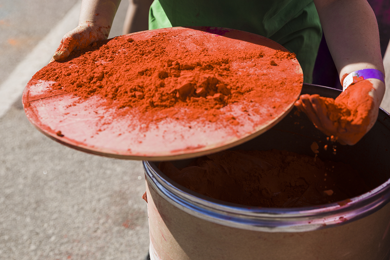 Photo of a person removing colored powder from a fiber drum