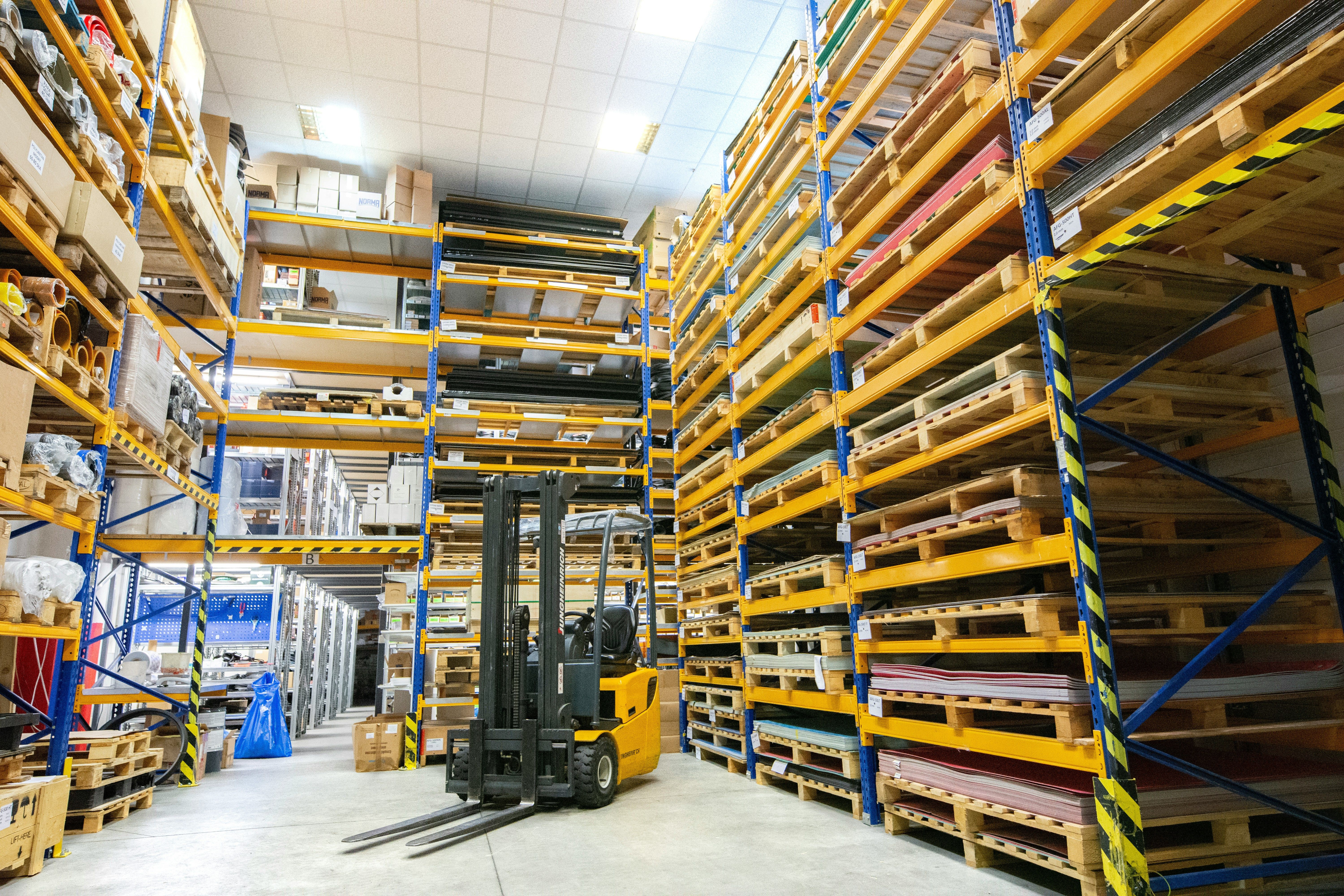 Forklift moving loaded plastic pallets through a warehouse distribution center