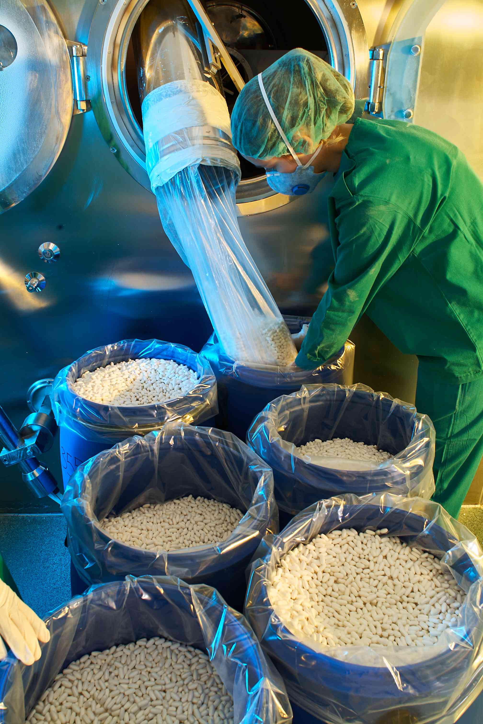 Photo of factory worker filling plastic drums with pills
