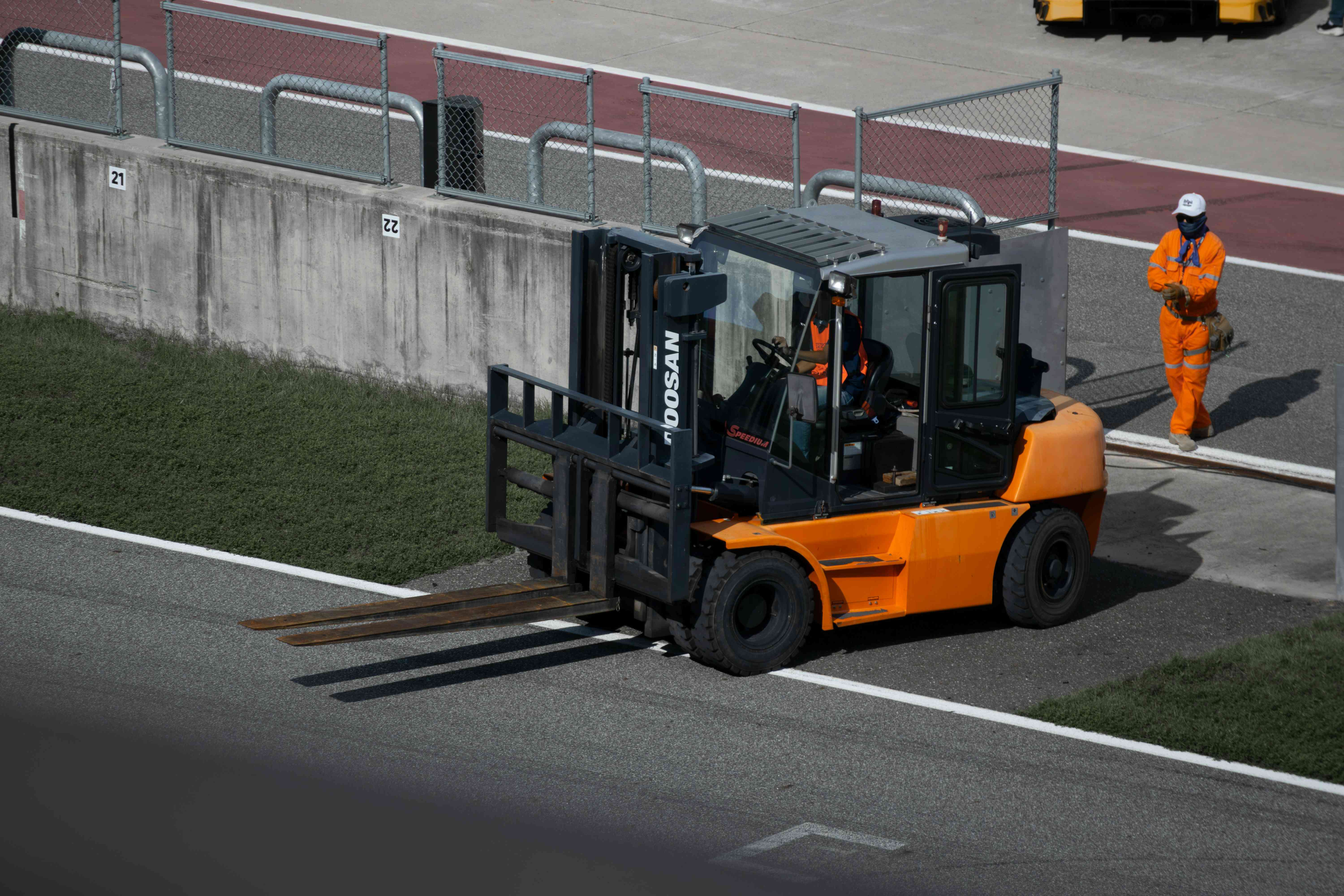 Forklift moving a loaded plastic pallet in a distribution yard