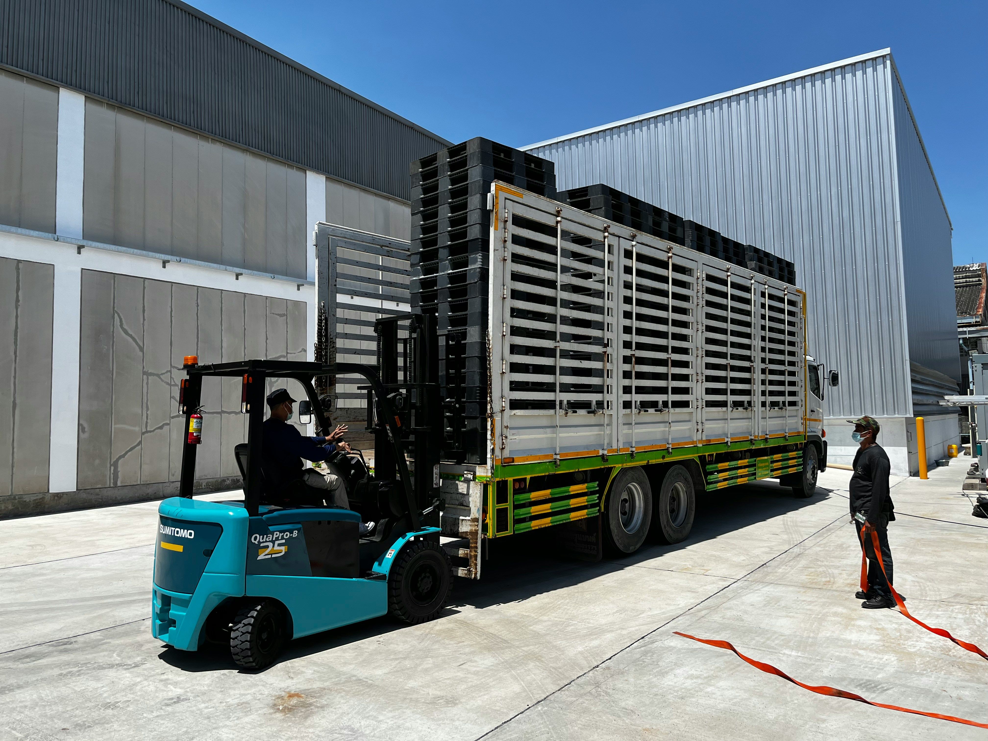 Forklift lifting plastic pallets inside a truck trailer