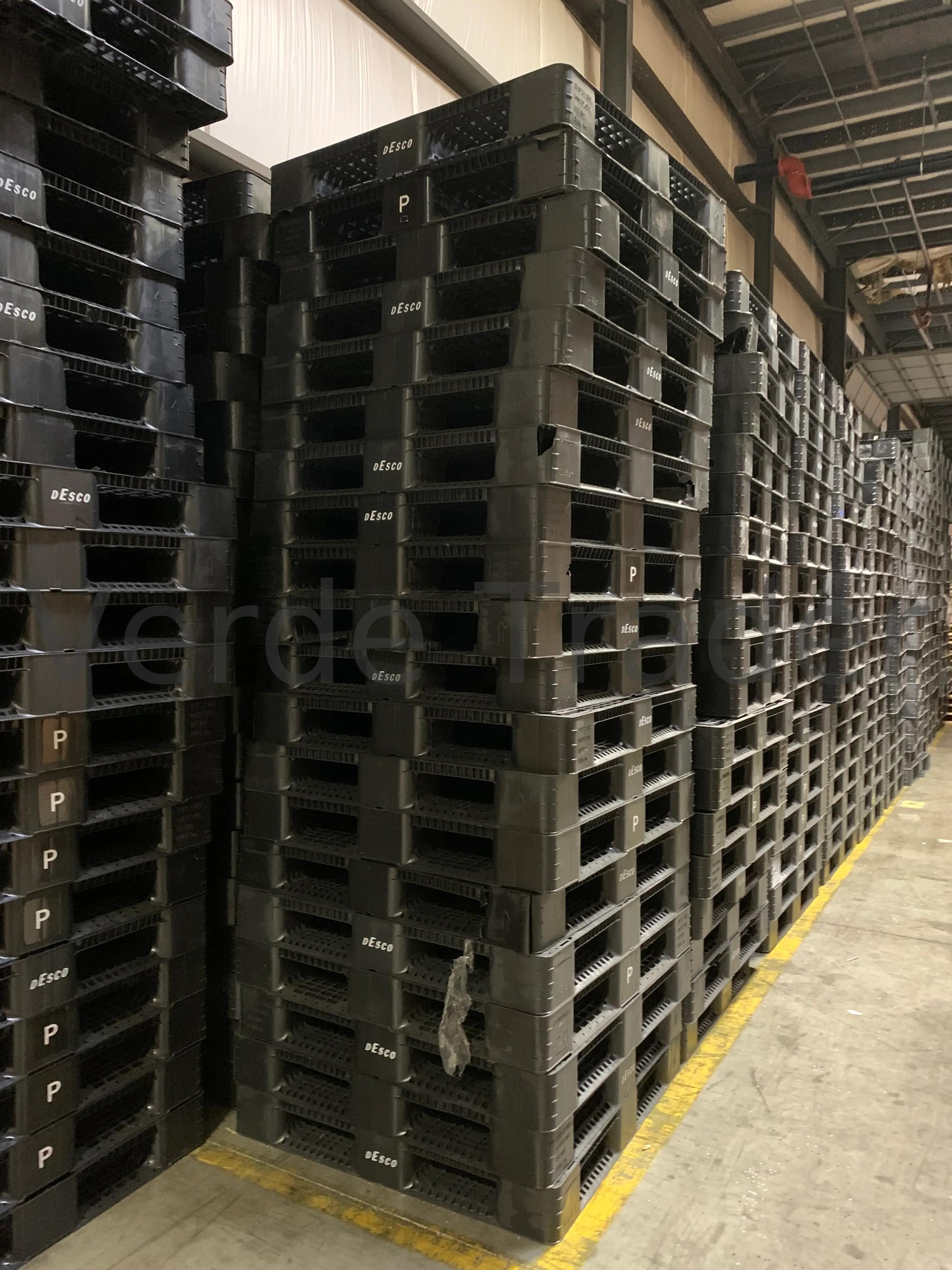 Stack of used stackable plastic pallets in a warehouse