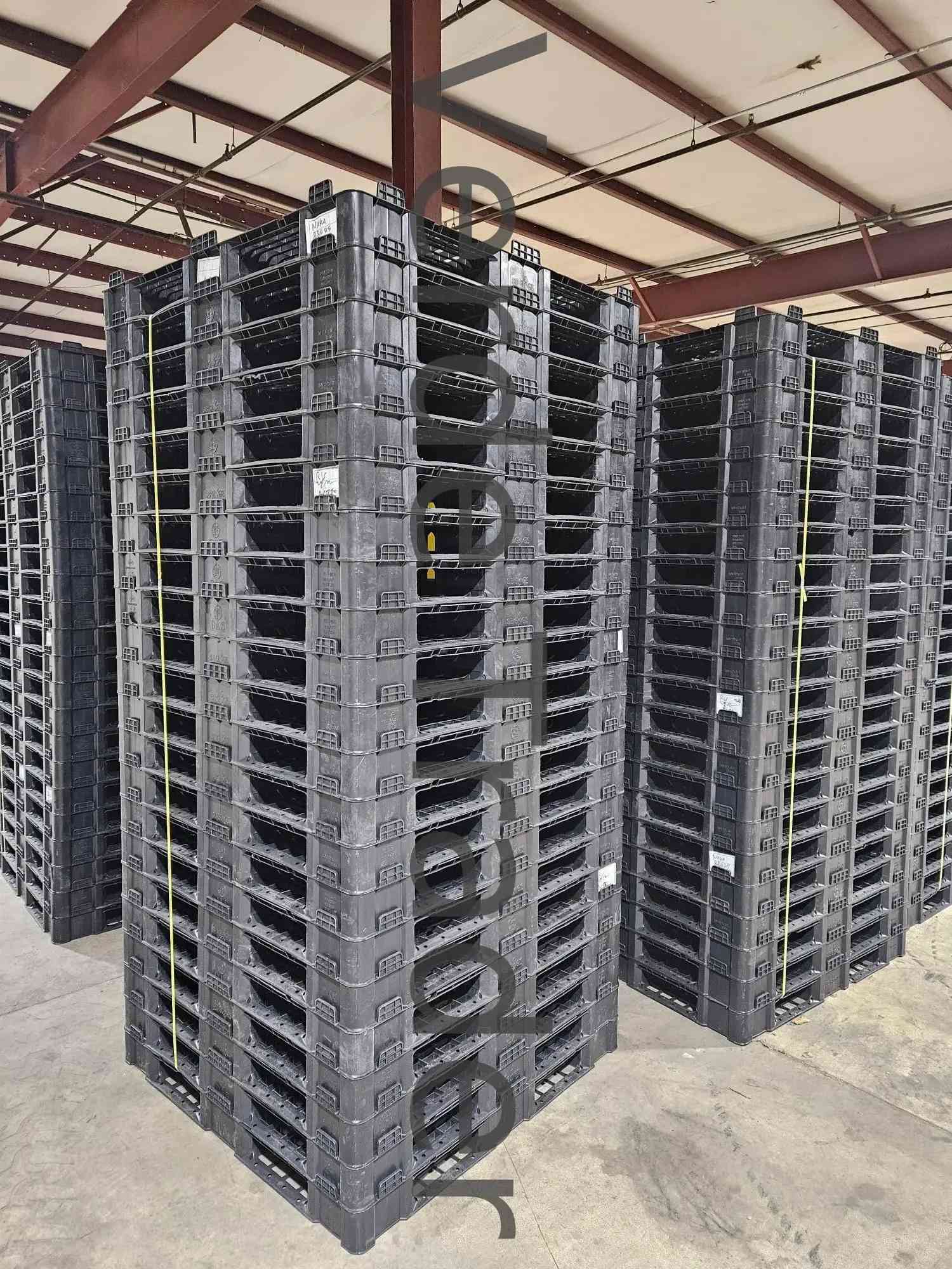 Loaded plastic pallets floor-stacked several units high in a warehouse
