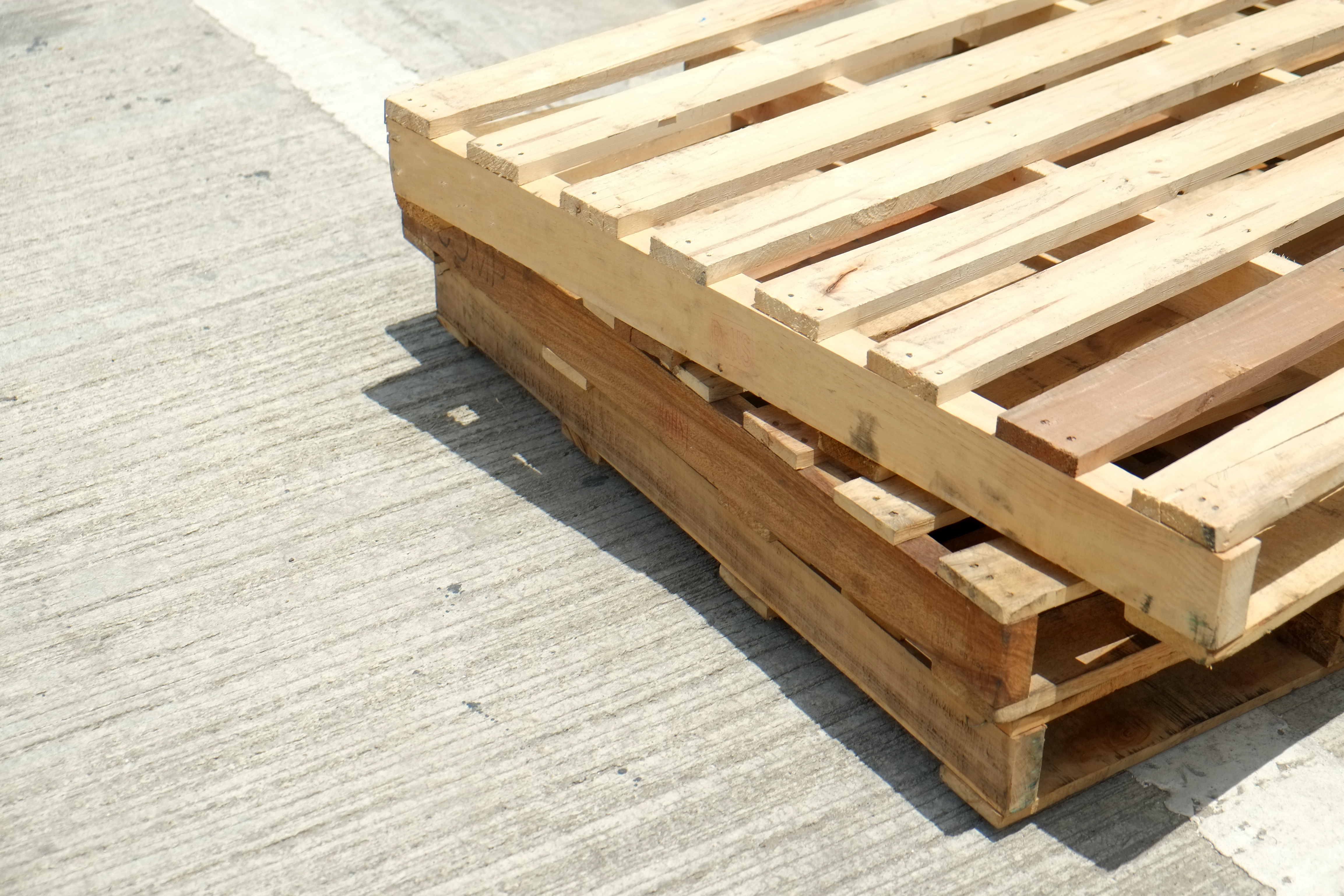 A Photo of Three Stringer Pallets on Cement