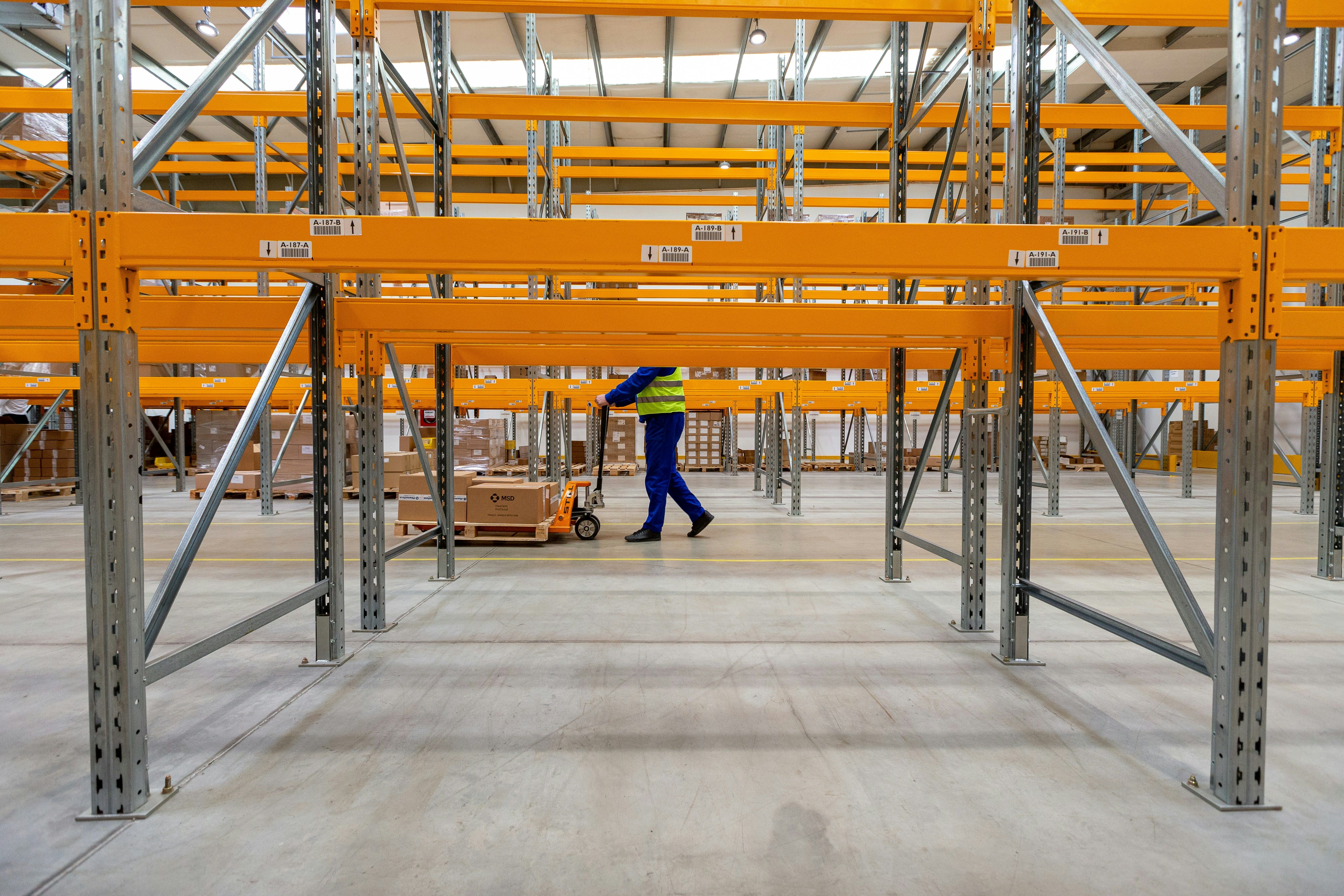 Plastic pallet on two-rail rack load test fixture showing deflection measurement setup