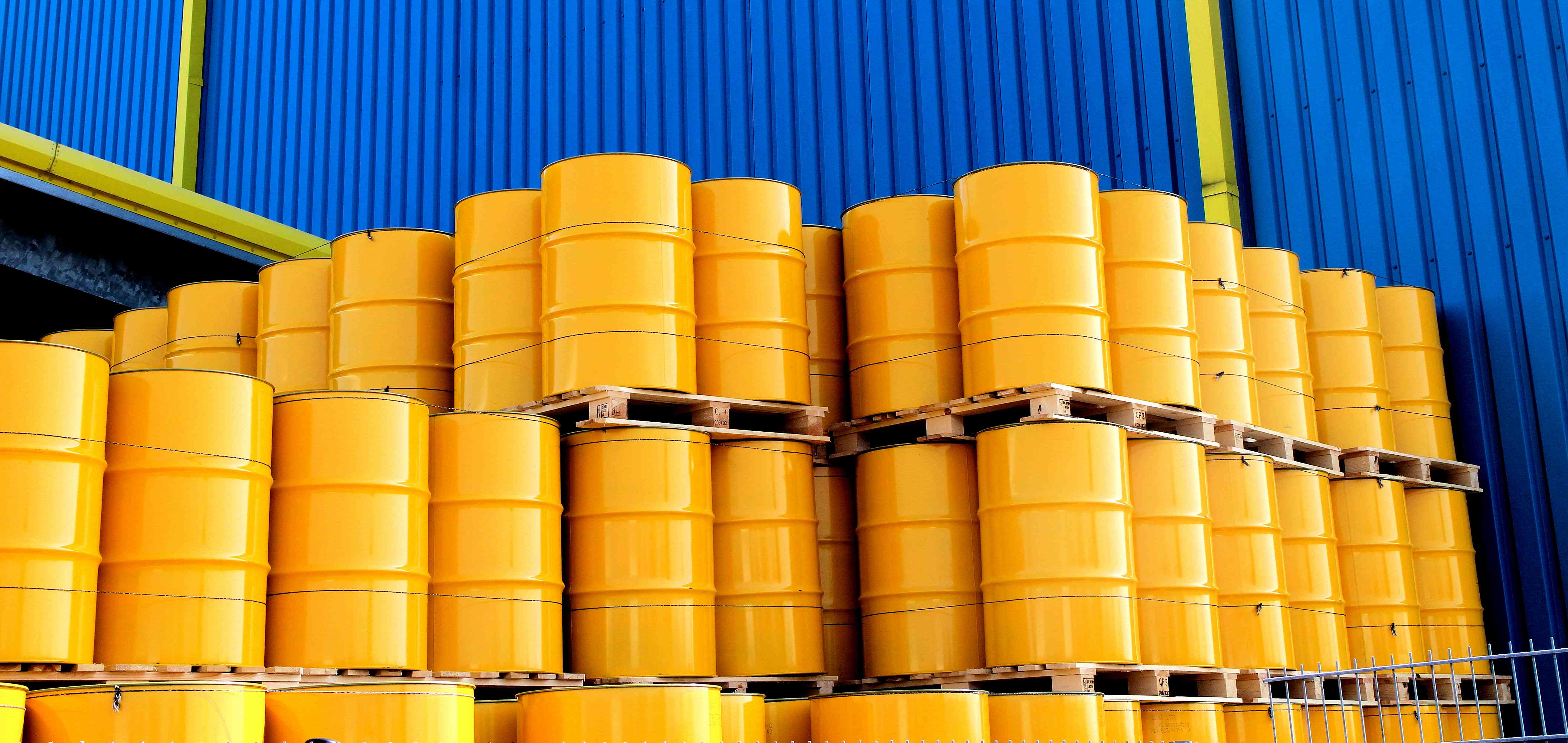 Photo of steel drums on pallets in front of a building