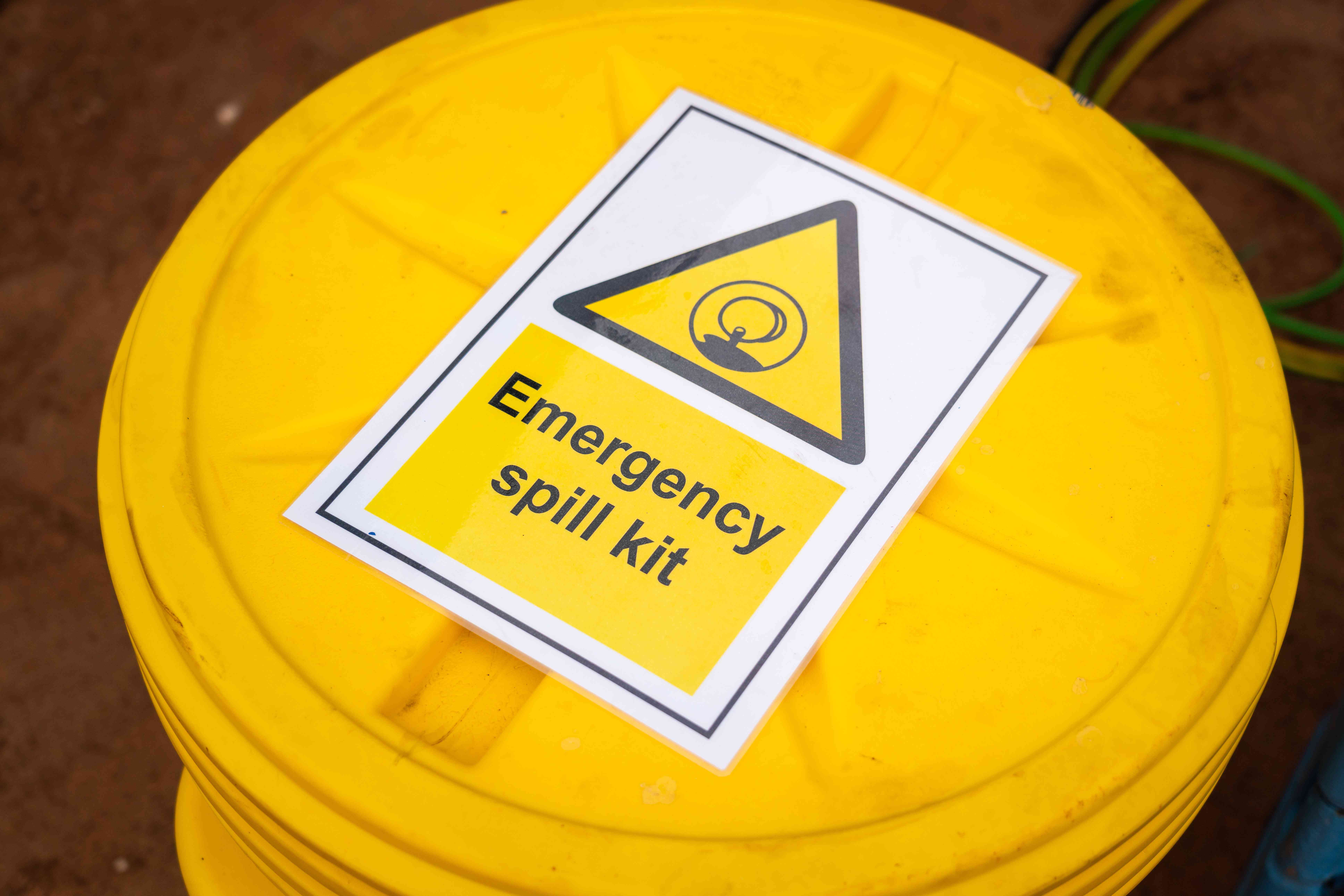 Photo of a yellow, lab pack plastic drum labeled "emergency spill kit"