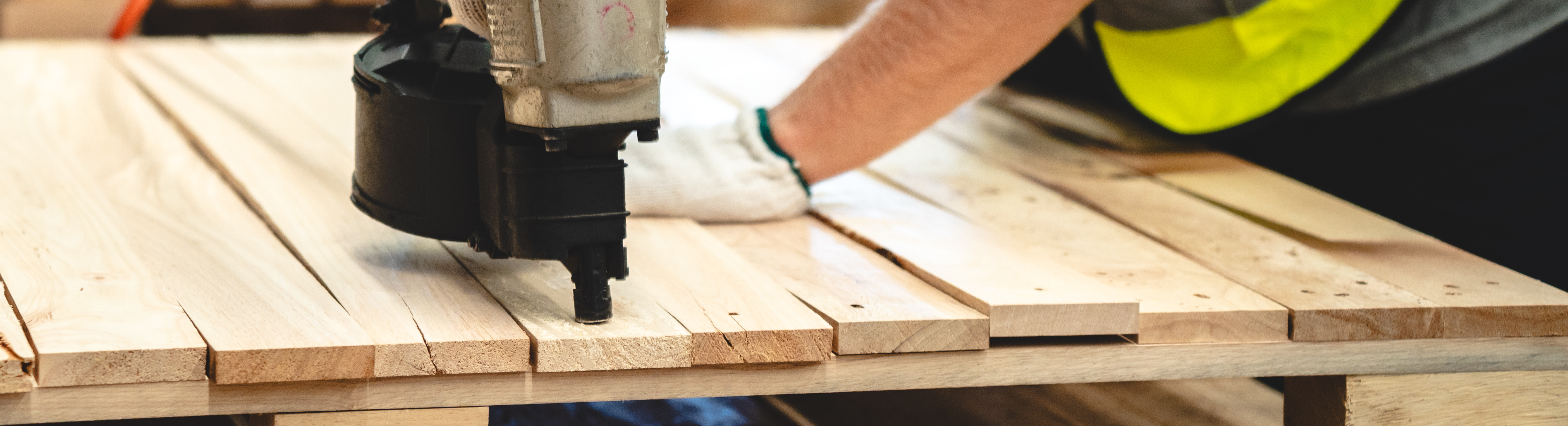 Photo of a man using a nail gun to build a wood pallet