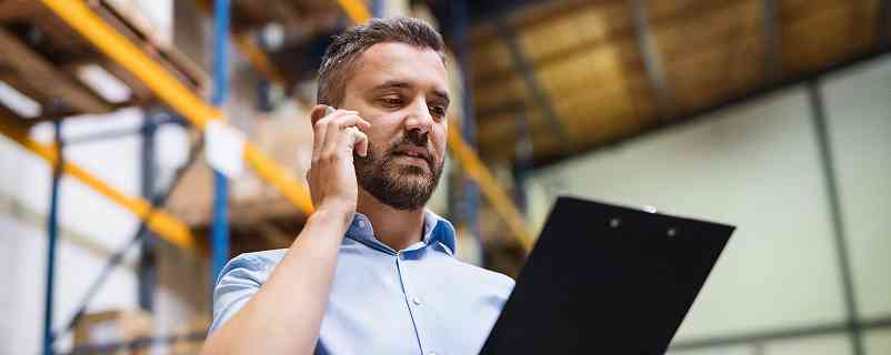 man talking on the phone and holding a clipboard