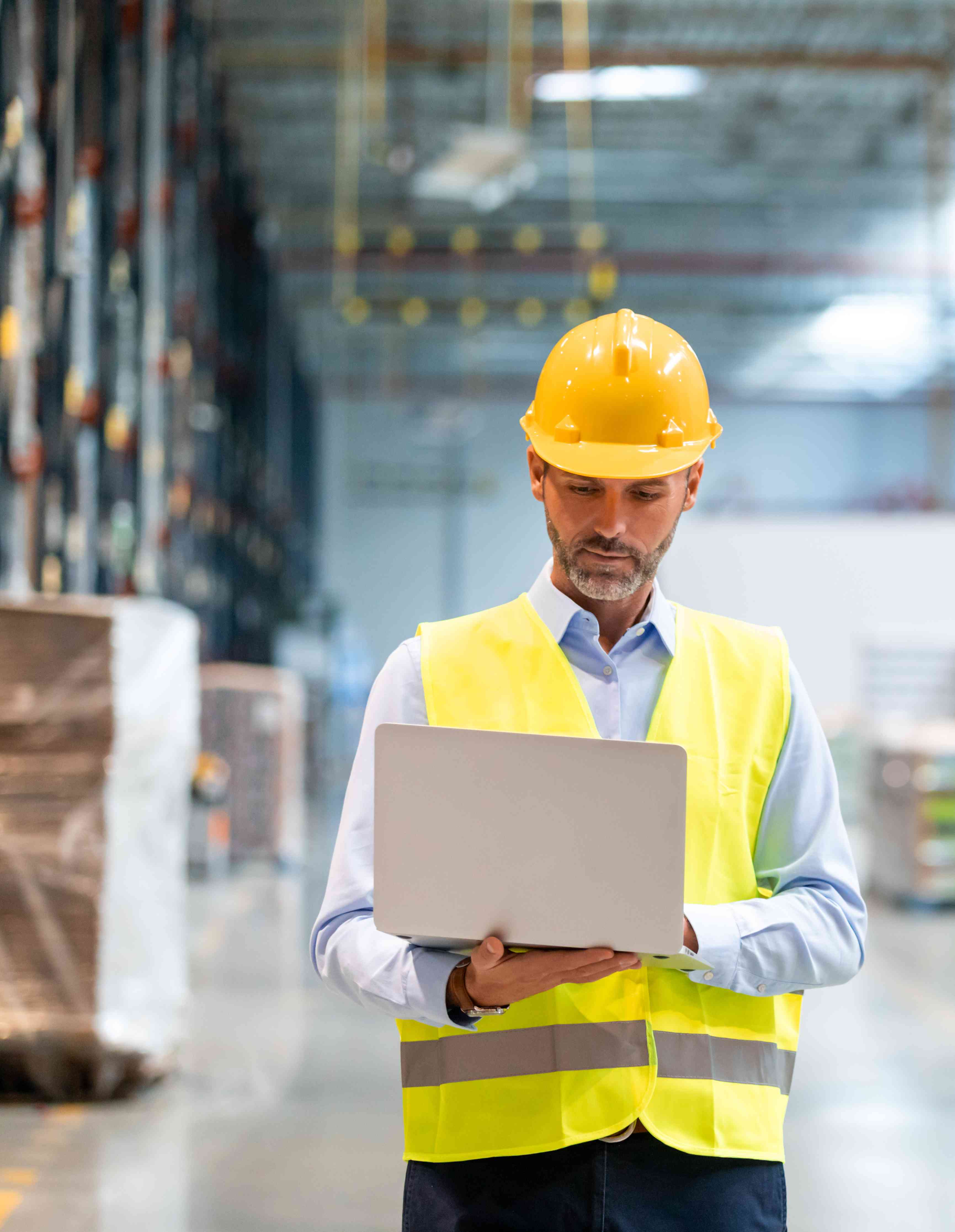 Photo of man wearing a hardhat and safety vest in a warehouse