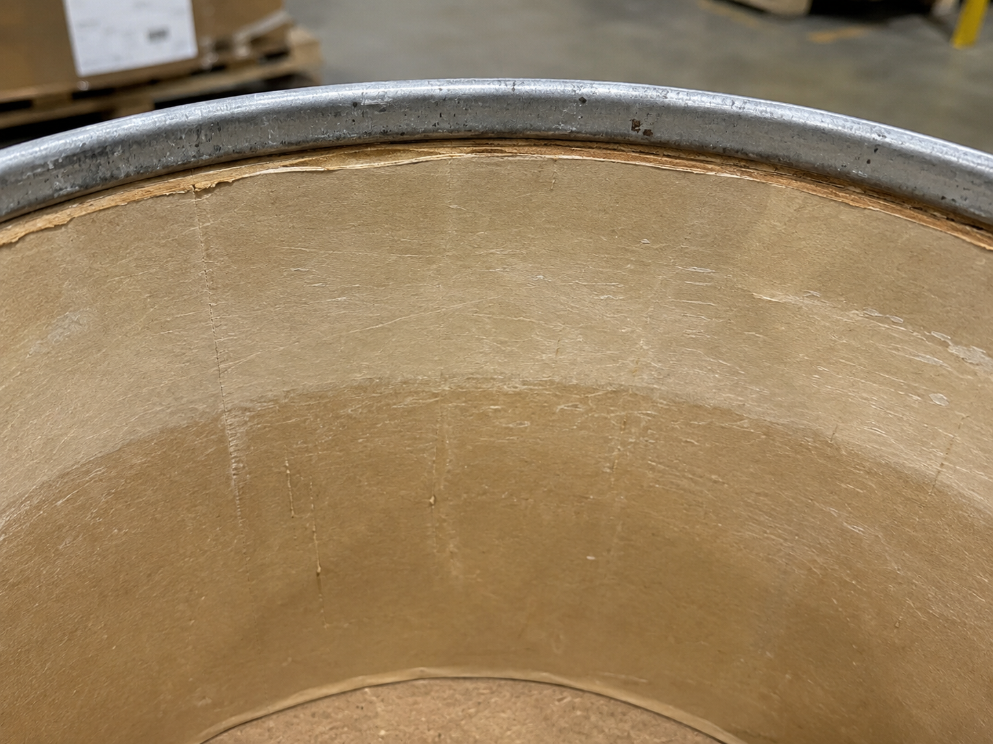 Close-up of a used fiber drum interior liner and metal chime showing wear