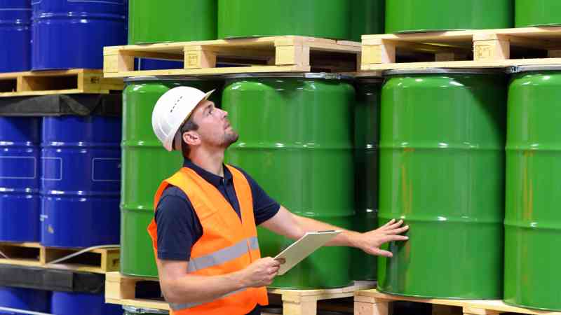 man looking at steel drums in a warehouse