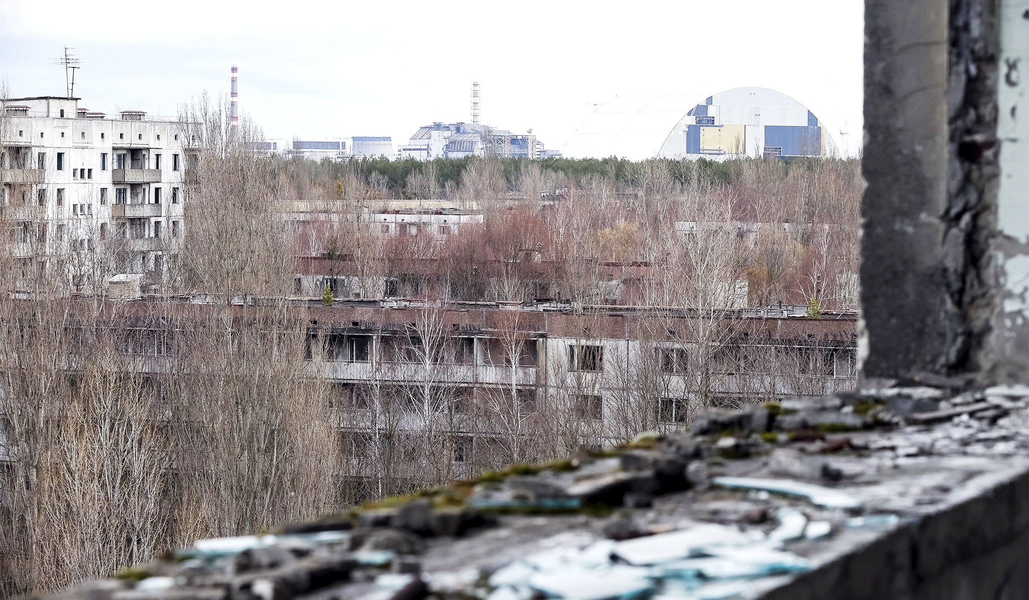 The containment shelter for the damaged fourth reactor (left) and the New Safe Confinement structure (right) at the Chernobyl nuclear power plant, seen from the abandoned city of Pripyat, March 23, 2016.
