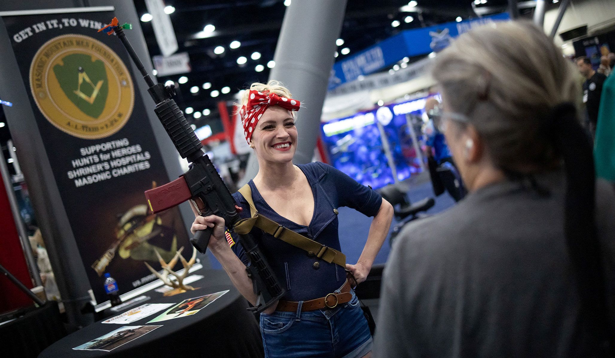 A staff member of an exhibitor's booth smiles at visitors during the National Rifle Association's annual meetings and exhibits in Houston, Texas, April 17, 2026.