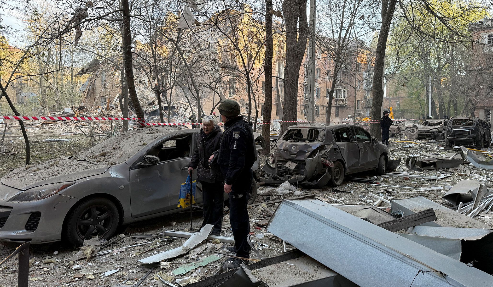 A police officer evacuates a resident at a site of an apartment building hit by a Russian drone and missile strike in Dnipro, Ukraine, April 25, 2026. Picture taken using a mobile phone.