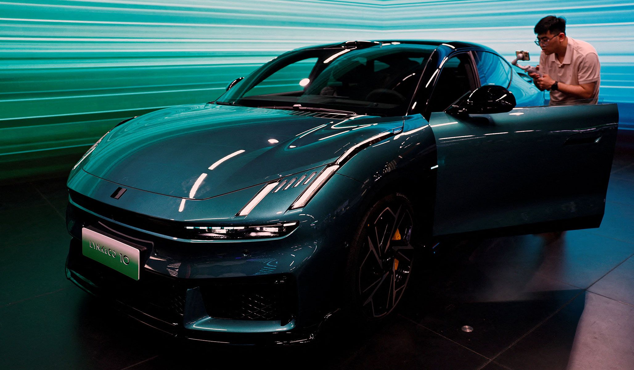 A man films the interior of a Lynk & Co 10 electric vehicle at the Beijing International Automotive Exhibition in Beijing, China, April 24, 2026.