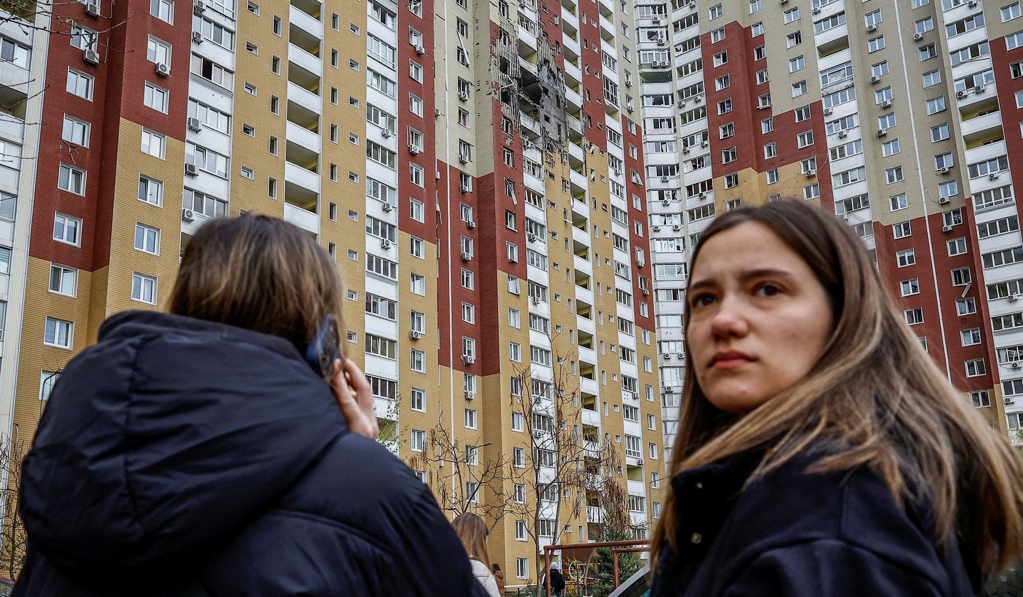 Residents stand near a residential building damaged during Russian drone strike in Kyiv, Ukraine, April 16, 2026.