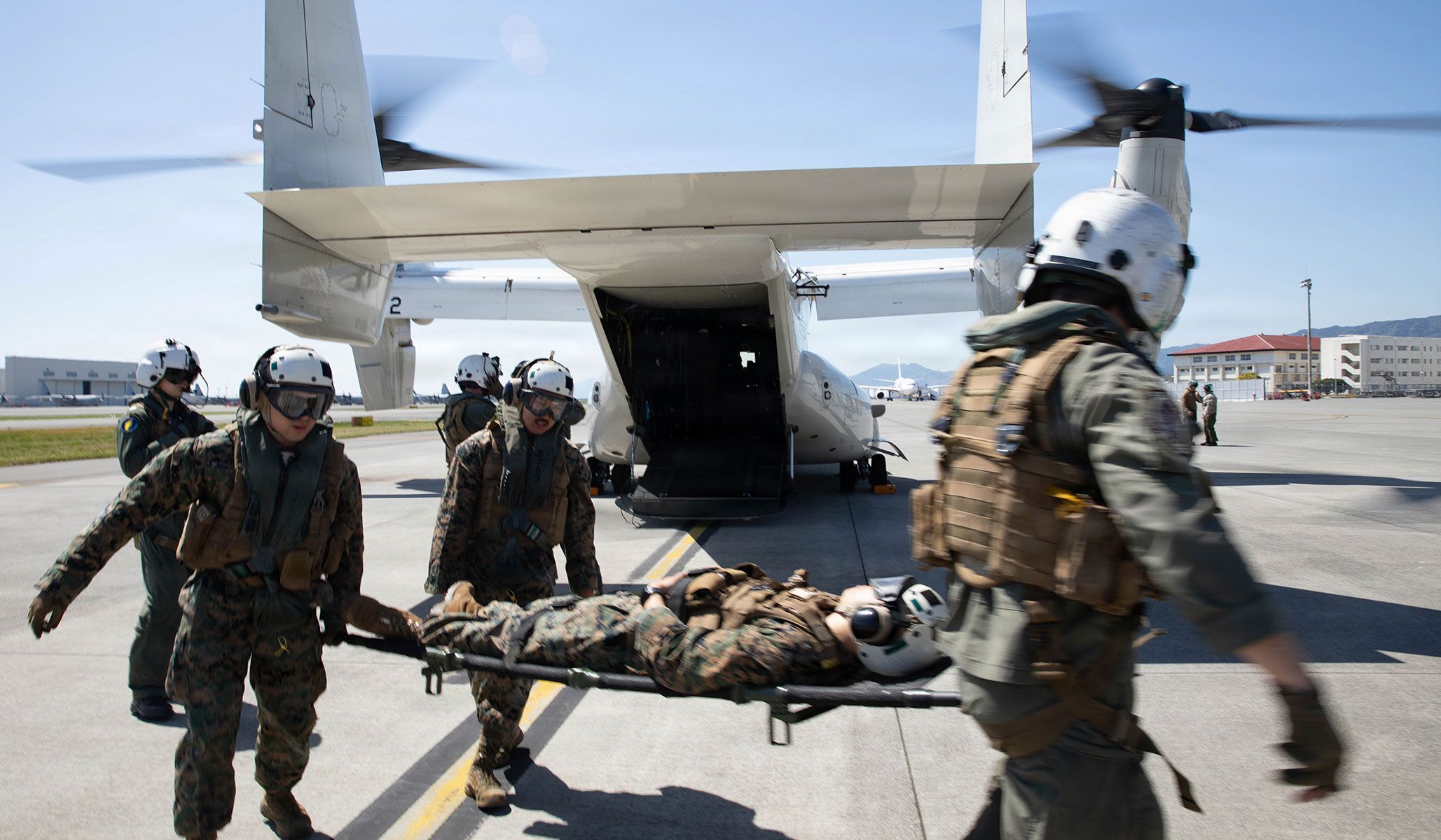 U.S. Navy sailors with Third Dental Battalion, Third Marine Logistics Group, and the “Titans” of Fleet Logistics Multi-Mission Squadron VRM-30, Carrier Air Wing CAW-5, carry and turn a simulated casualty towards a U.S. Navy CMV-22B Osprey assigned to VRM-30 for a simulated casualty evacuation during Exercise Shika-X 26 at Marine Corps Air Station Iwakuni, Japan, April 16, 2026.