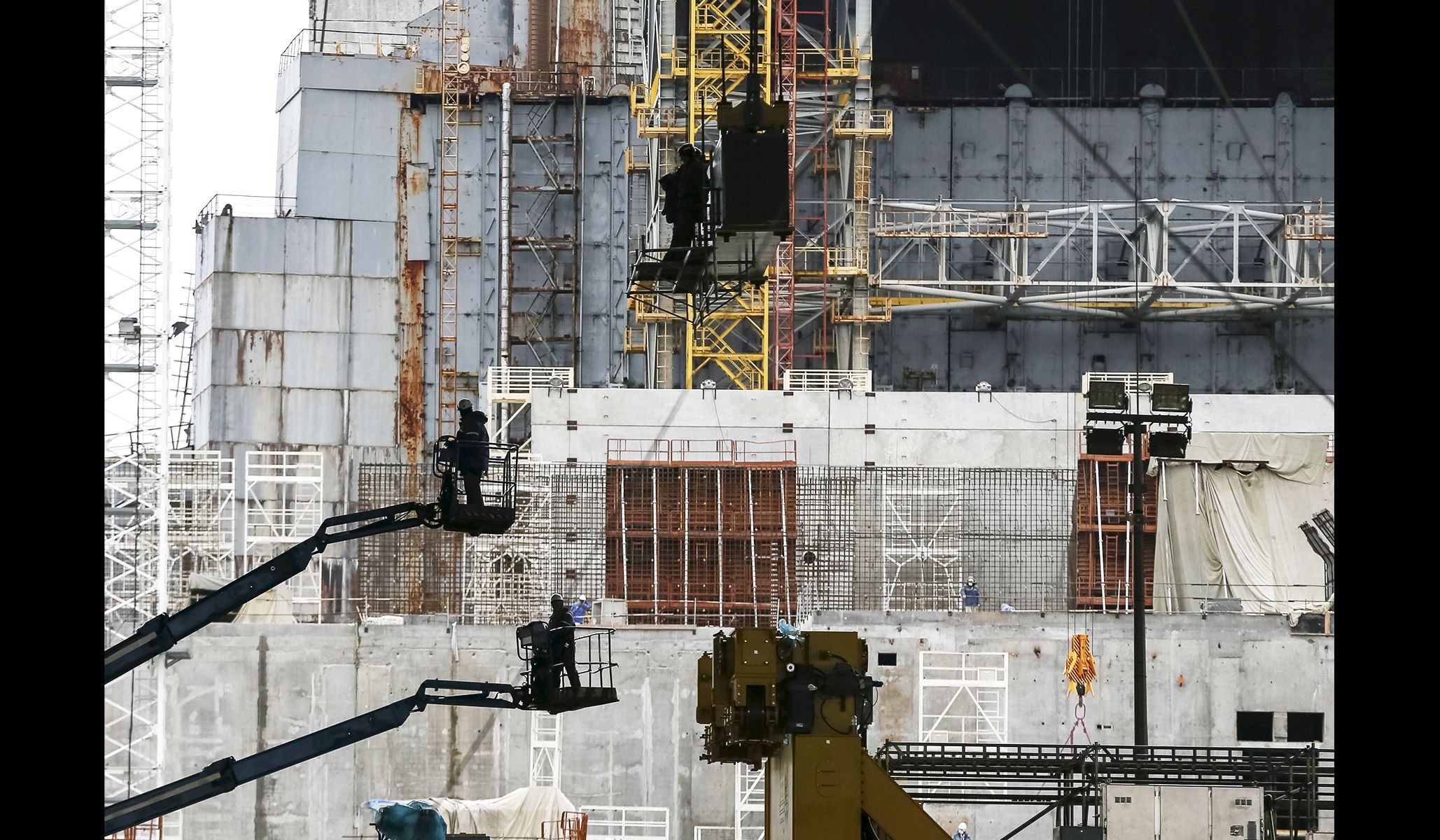 Employees work in front of the sarcophagus covering the damaged fourth reactor at the Chernobyl nuclear power plant in Ukraine, March 23, 2016.