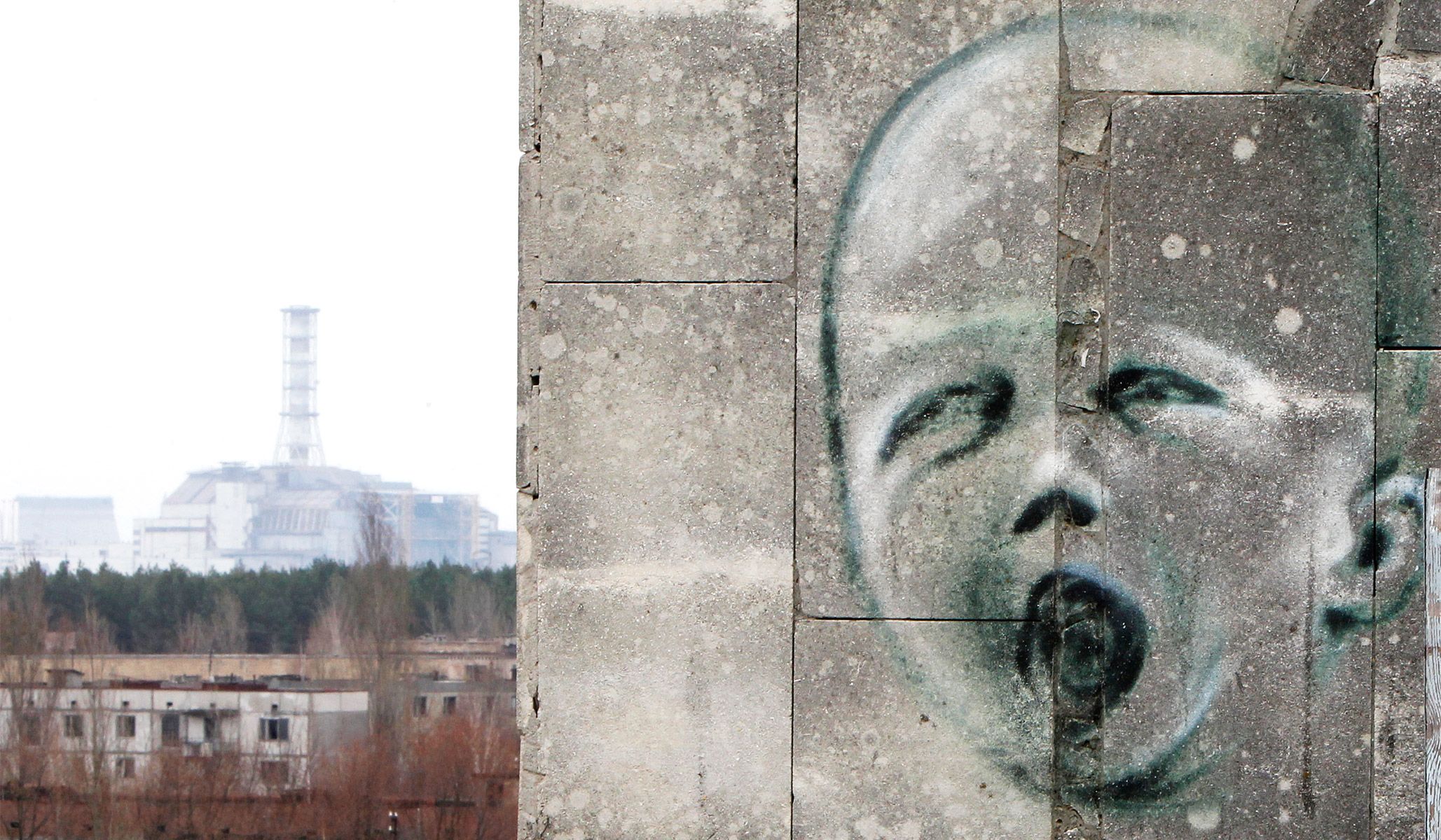 The sarcophagus covering the damaged fourth reactor at the Chernobyl nuclear power plant visible in the distance beyond graffiti on a building in the abandoned city of Pripyat, April 4, 2011.