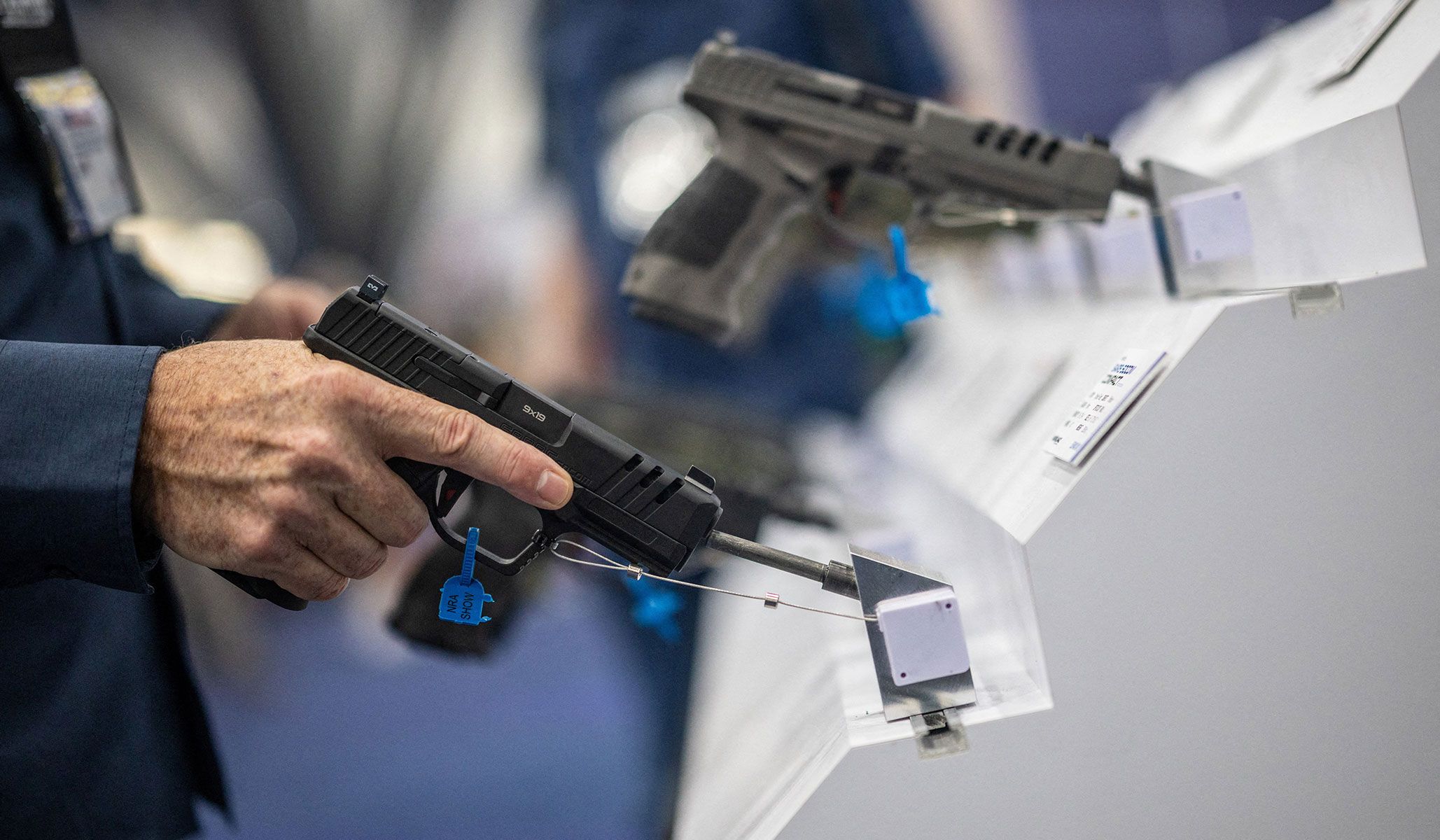 A visitor handles a gun at an exhibition booth during the National Rifle Association's annual meetings and exhibits in Houston, Texas, April 17, 2026.