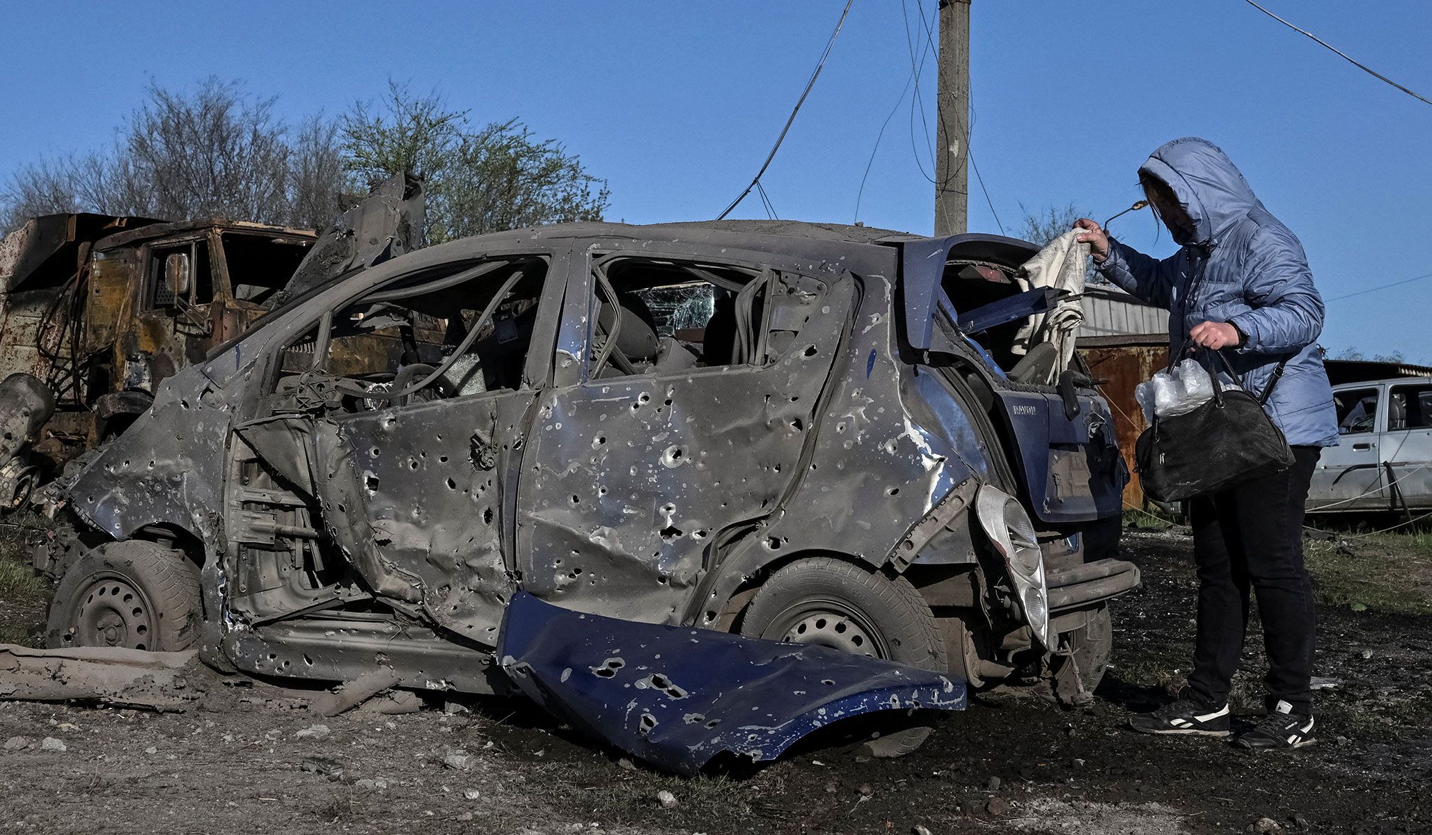 A resident inspects her destroyed car at the site of a Russian combined military strike in Zaporizhzhia, Ukraine, April 15, 2026.