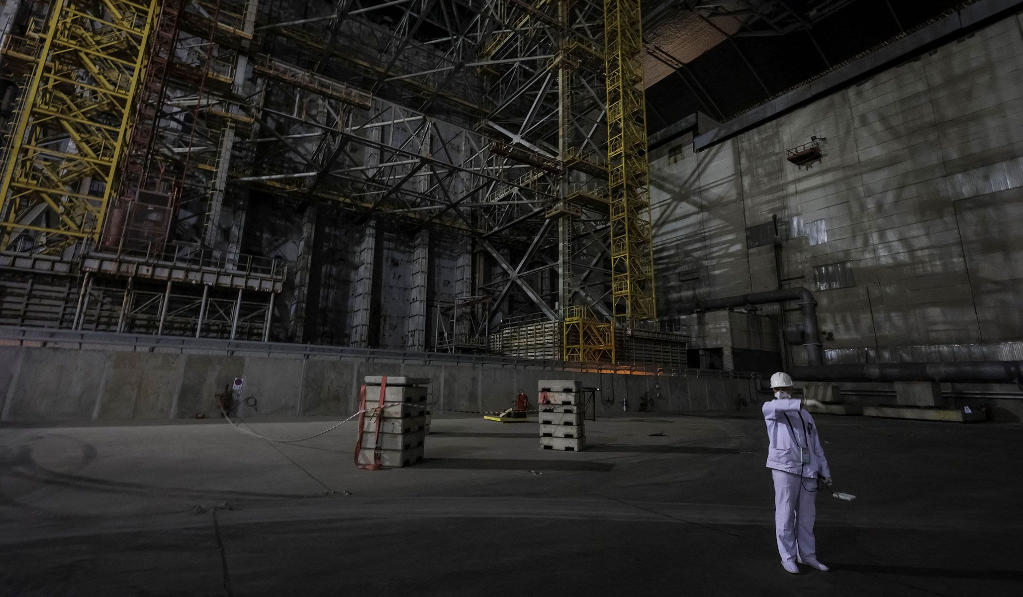 An employee measures a radiation level next to the old sarcophagus covering the damaged fourth reactor under the New Safe Confinement Structure at the Chernobyl nuclear power plant in Kyiv Region, Ukraine, April 22, 2026.