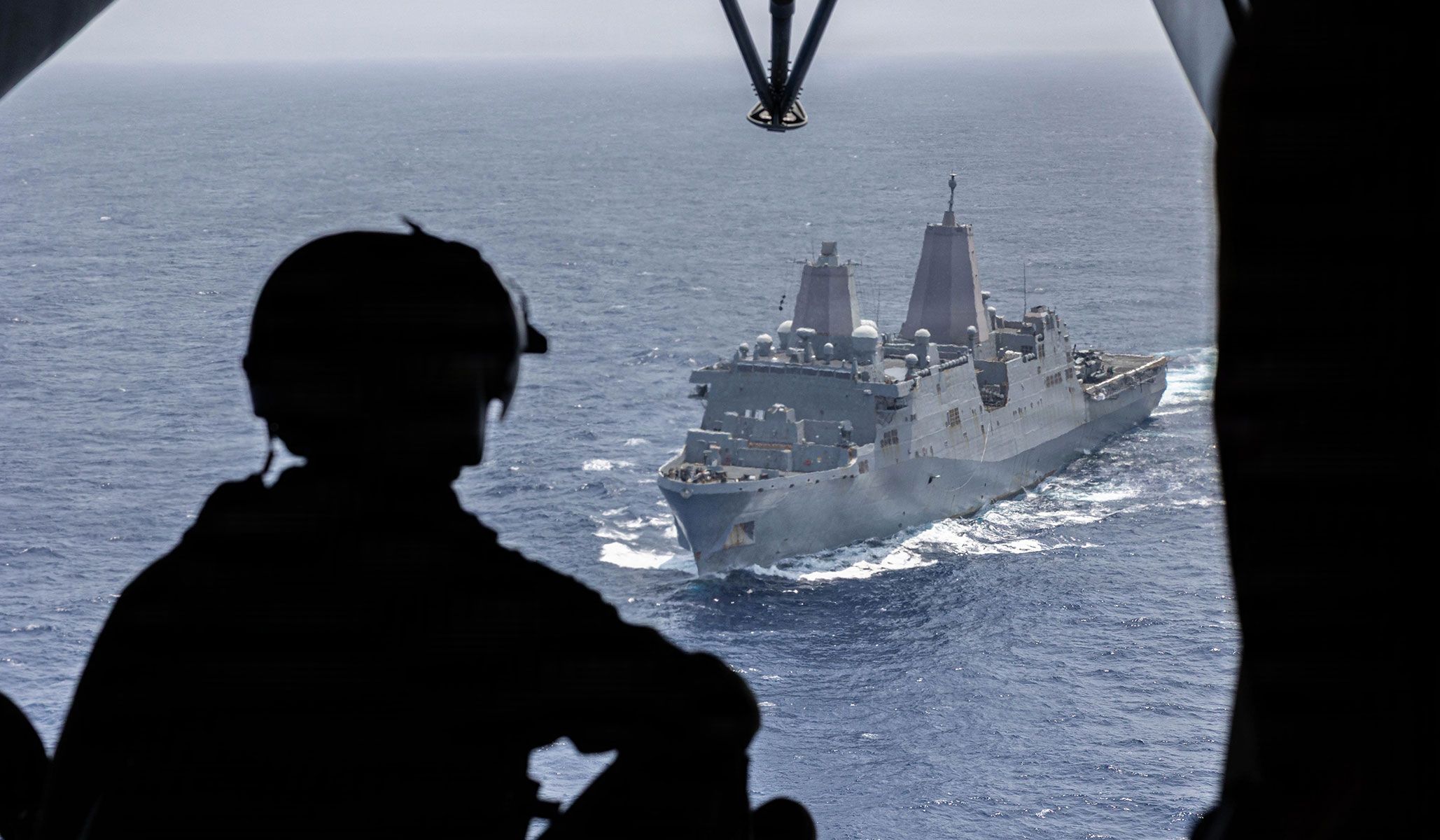 U.S. Marine Corps Corporal Isaac Johnson, a crew chief with the “Evil Eyes” of Marine Medium Tiltrotor Squadron VMM-163 (Reinforced), 11th Marine Expeditionary Unit, observes the San Antonio-class amphibious transport dock ship USS <i>Portland</i> (LPD-27) in the Pacific Ocean, April 18, 2026.