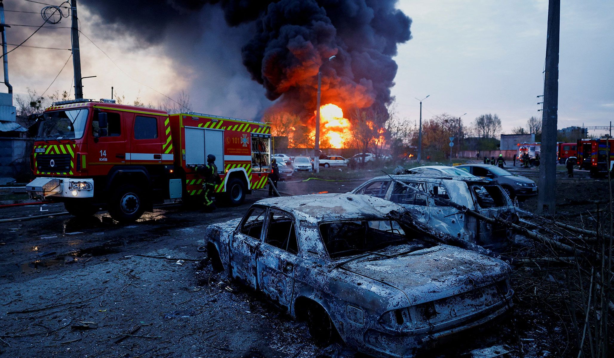Firefighters work next to destroyed vehicles at the site of a Russian missile strike in Kyiv, Ukraine, April 16, 2026.