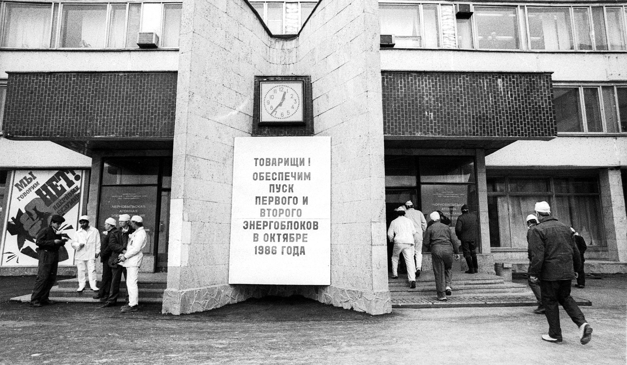 Workers enter the Chernobyl nuclear power plant weeks after the 1986 explosion. The sign reads: “Comrades, we guarantee the launch of the first and second bloc by October 1986,” referring to the first and second reactor that were switched off after the accident.