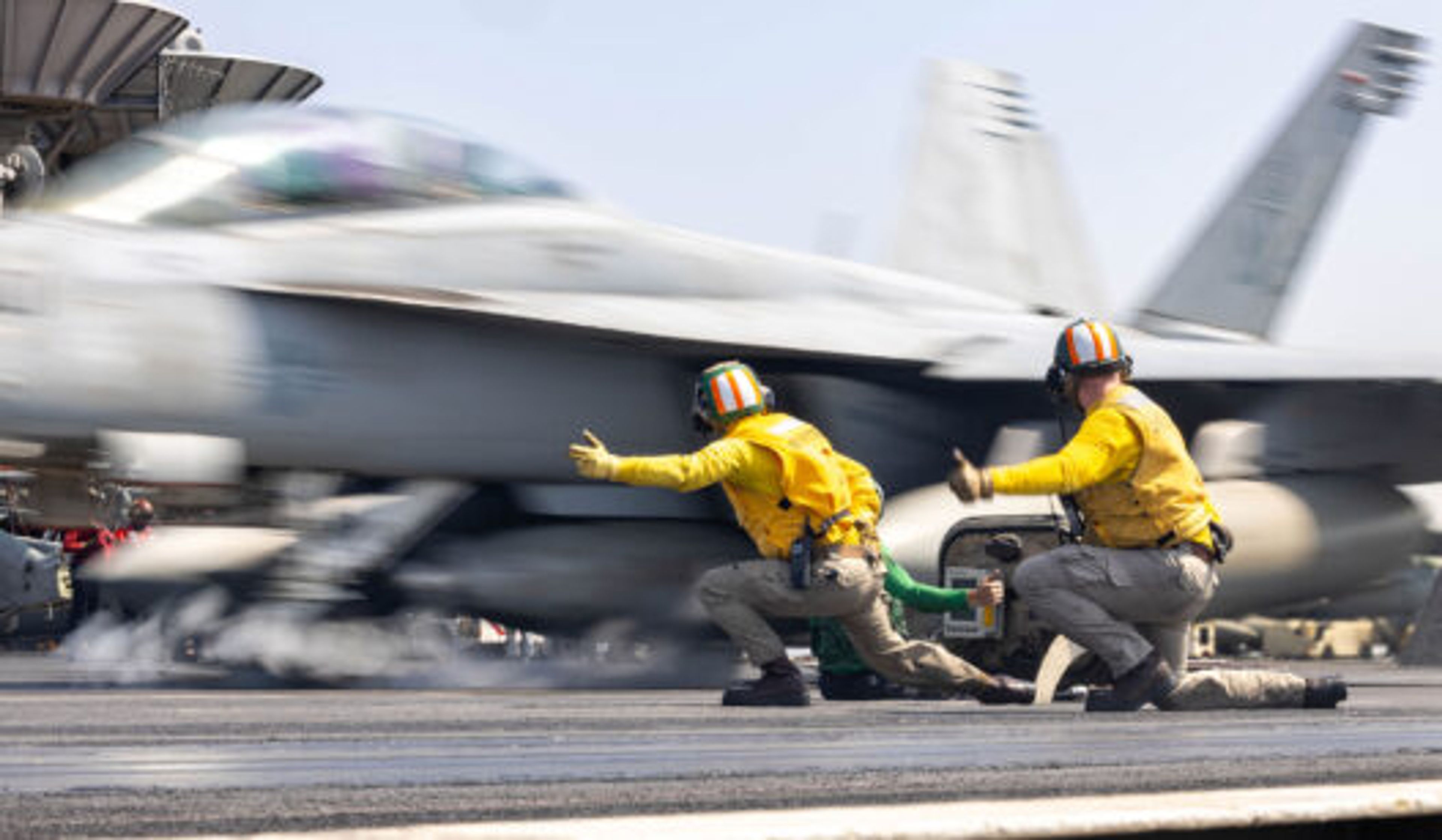 Two U.S. Navy catapult officers signal an F/A-18F Super Hornet to launch from the flight deck of the USS Harry S. Truman , under way in the U.S. Central Command area of responsibility, March 13, 2025.
