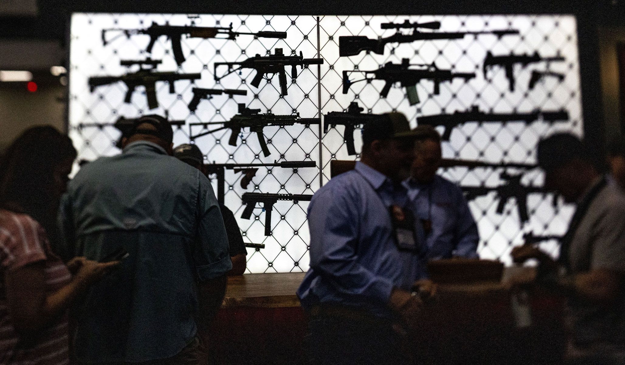 Visitors stand by an exhibit booth with assault rifles during the National Rifle Association's annual meetings and exhibits in Houston, Texas, April 17, 2026.