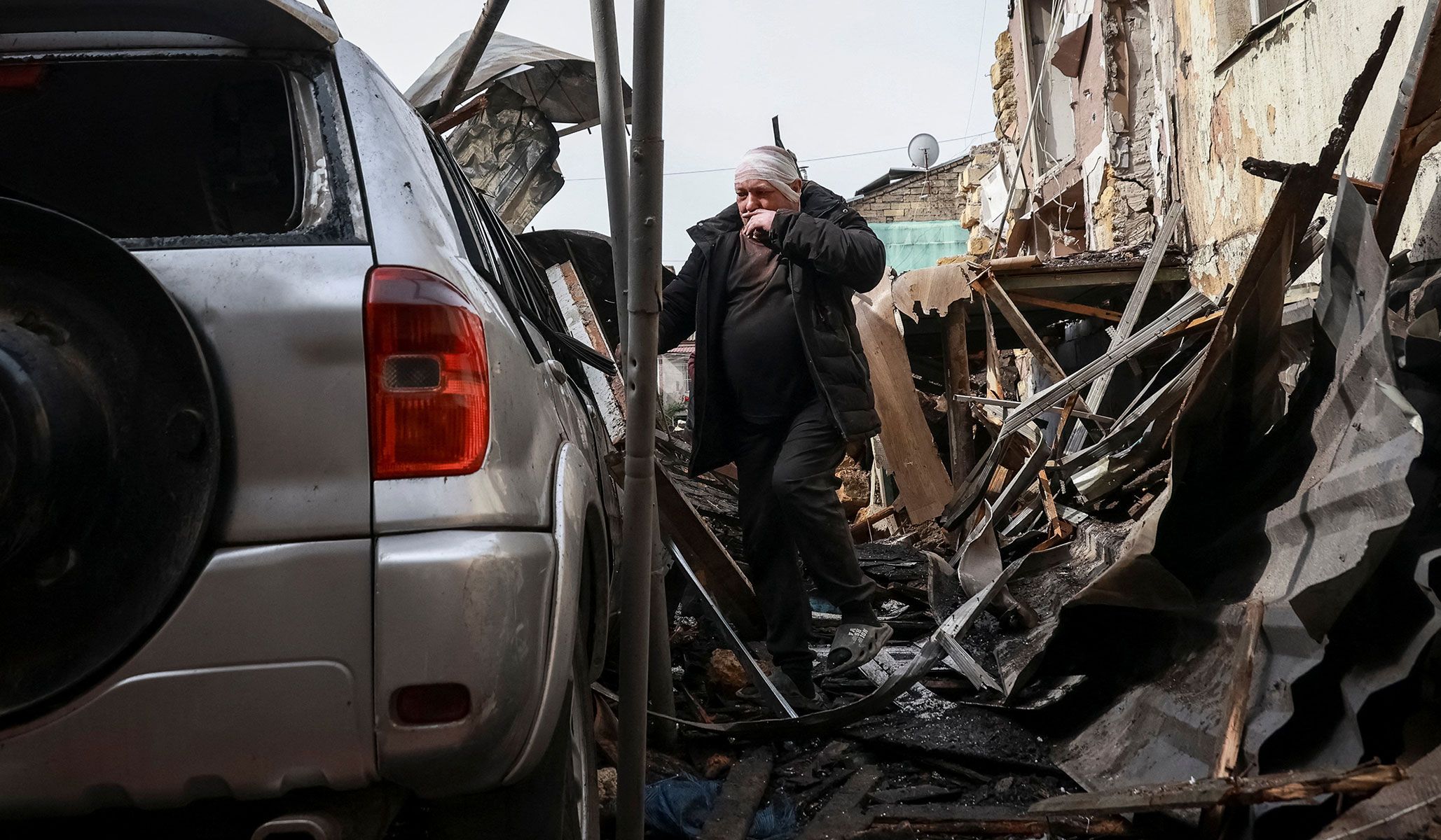 A wounded resident observes his damaged car near an apartment building hit by a Russian drone strike in Odesa, Ukraine, April 24, 2026.