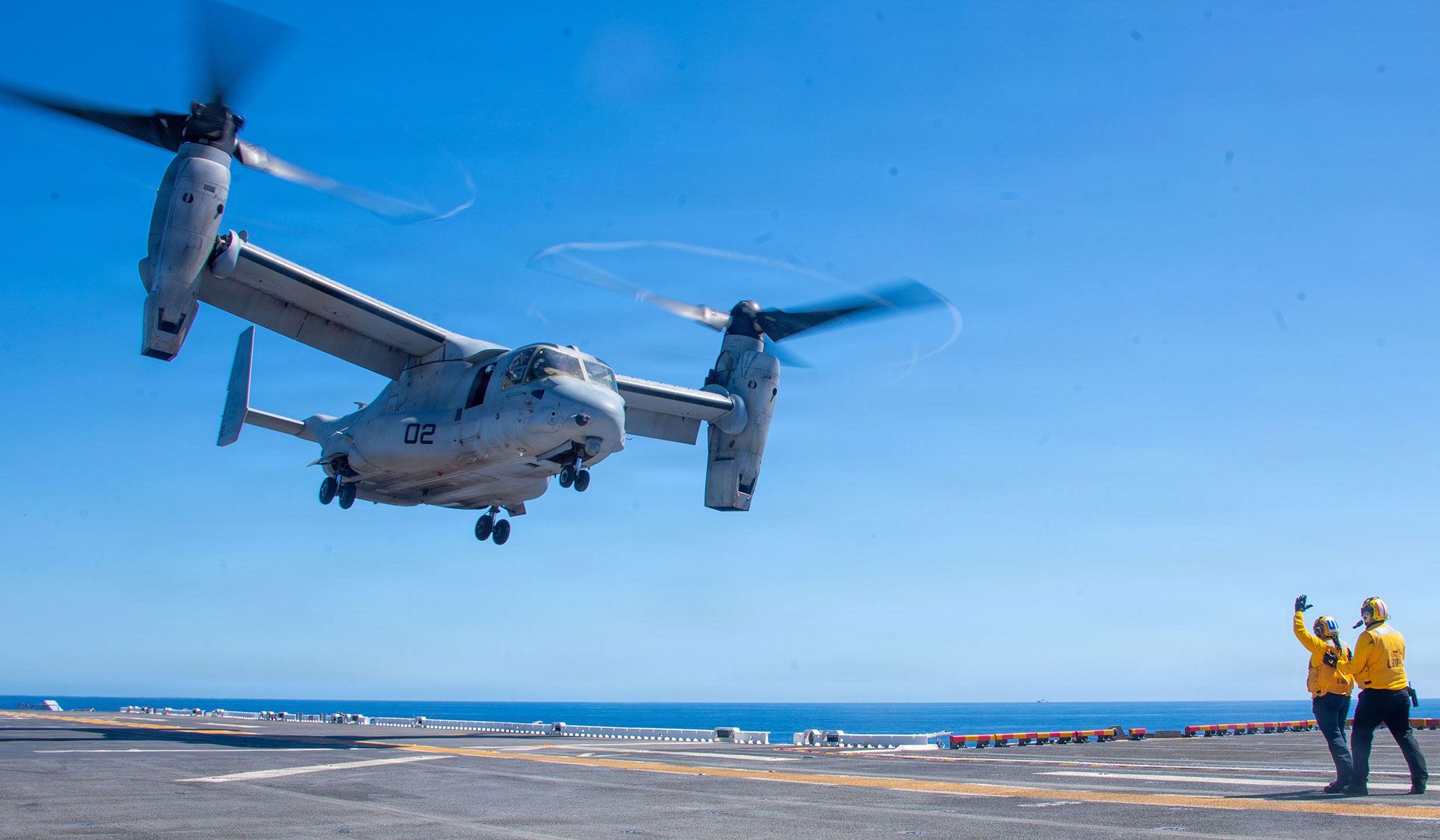 U.S. Navy Aviation Boatswain’s mate (Handling) Third Class Maritza Valdez (left) and Aviation Boatswain’s Mate (Handling) Second Class Hercules Soder, both assigned to the Wasp-class Amphibious assault ship USS <i>Essex</i> (LHD-2), direct an MV-22B Osprey assigned to the "Knightriders" of Marine Medium Tiltrotor Squadron VMM-164, to land on the flight deck during flight operations in the Pacific Ocean, April 14, 2026.