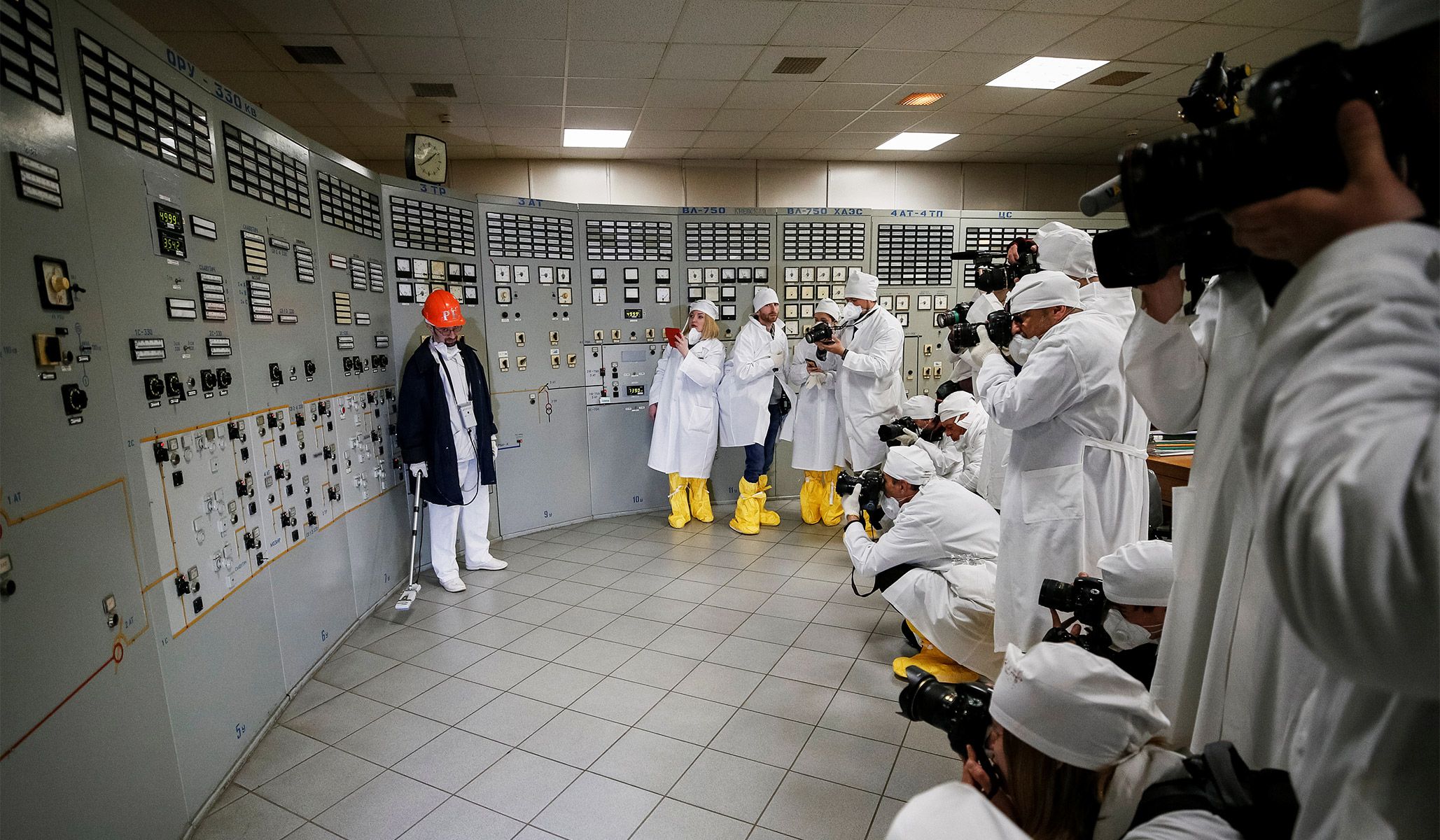 An employee measures the radiation level as journalists take pictures at a control center of the stopped third reactor at the Chernobyl nuclear power plant in Chernobyl, Ukraine, April 20, 2018.