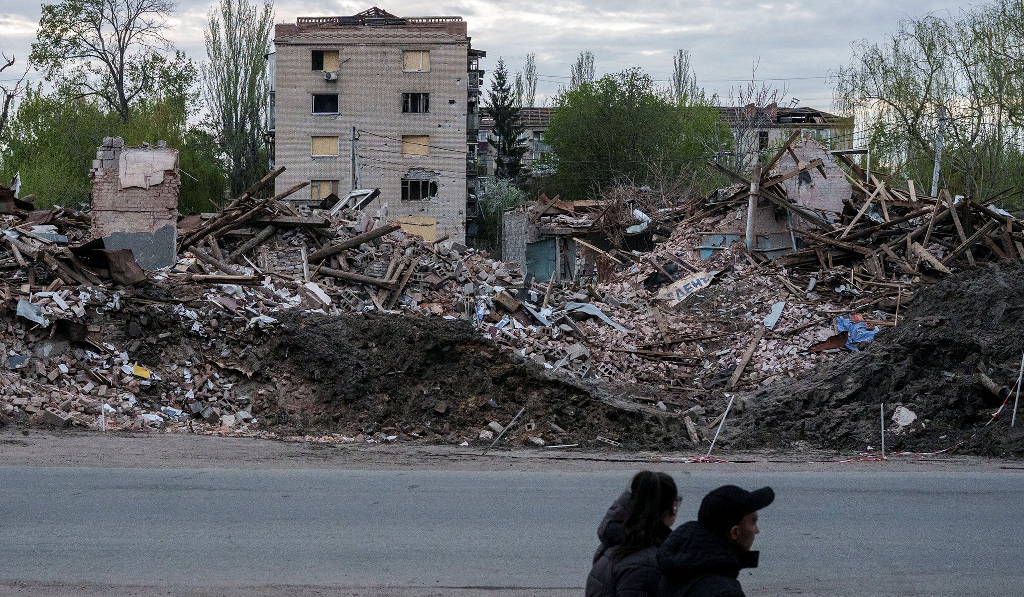 People walk next to destroyed buildings in the city of Sloviansk in Donetsk Region, Ukraine, April 25, 2026.