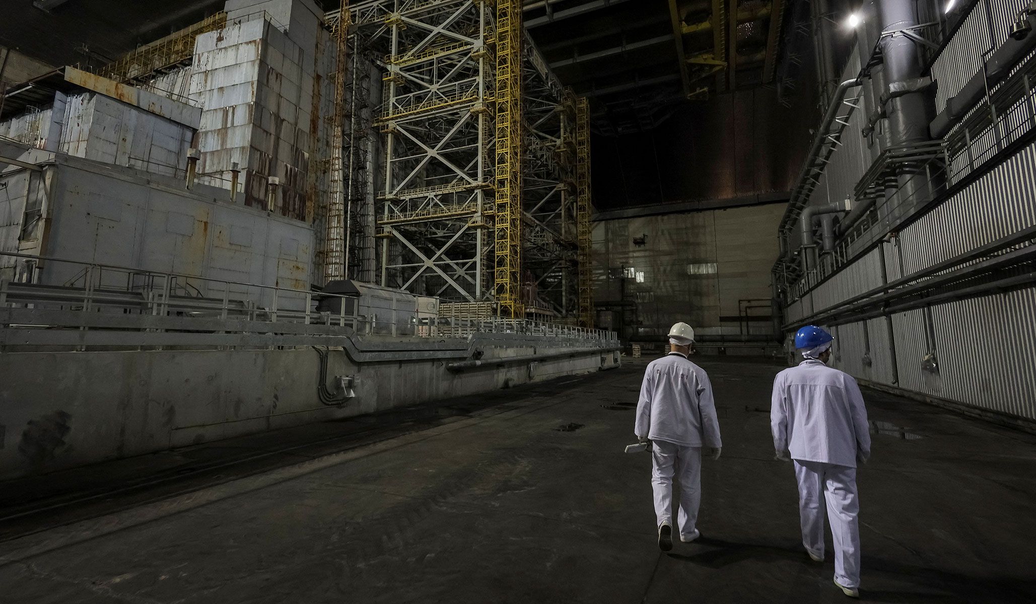 Employees walk next to the old sarcophagus covering the damaged fourth reactor under the New Safe Confinement Structure at the Chernobyl nuclear power plant in Kyiv Region, Ukraine, April 22, 2026.