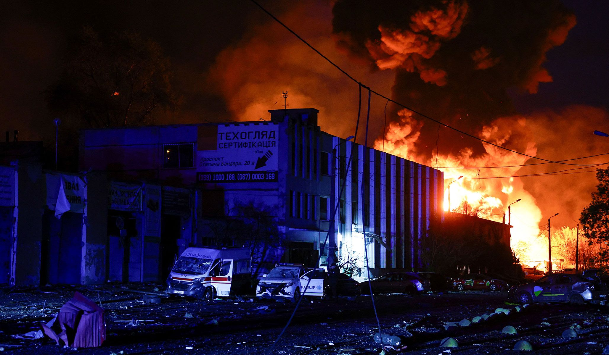 A police officer stands next to a police car and an ambulance vehicle which were damaged during a Russian missile strike in Kyiv, Ukraine, April 16, 2026.