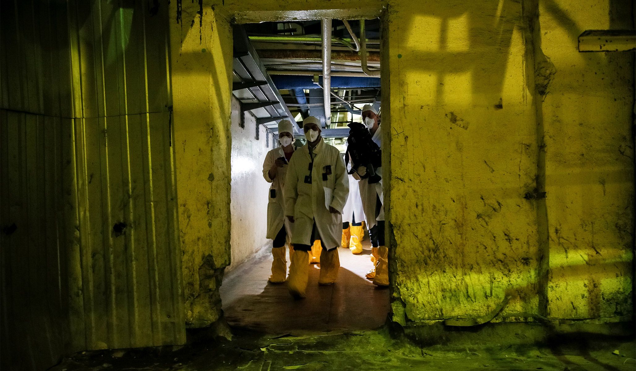 An employee and journalists walk through a corridor of the stopped third reactor at the Chernobyl nuclear power plant in Chernobyl, Ukraine, April 20, 2018.