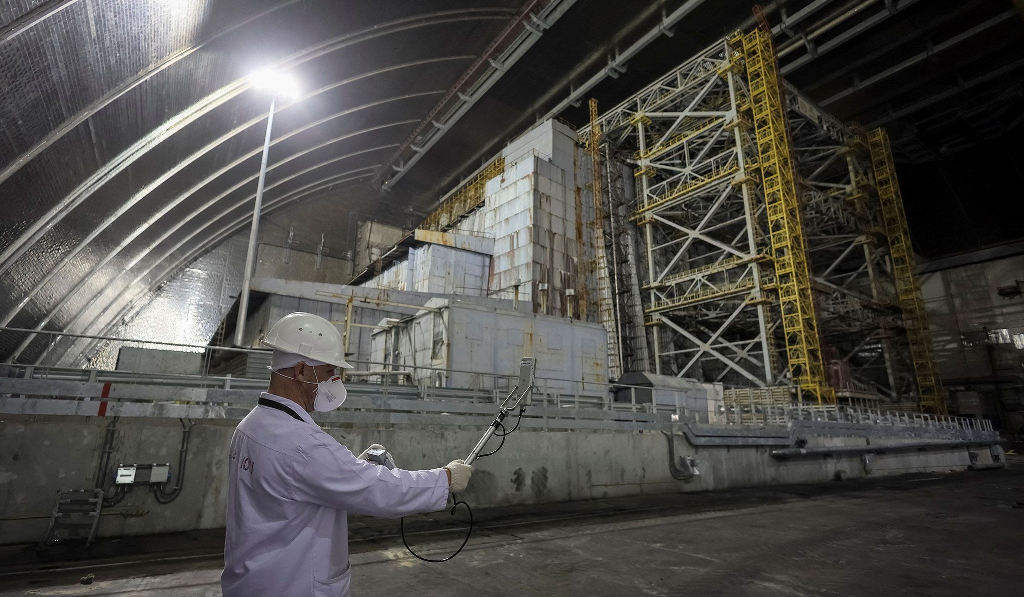 An employee measures the radiation level next to the old sarcophagus covering the damaged fourth reactor under the New Safe Confinement Structure at the Chernobyl nuclear power plant in Kyiv Region, Ukraine, April 22, 2026.