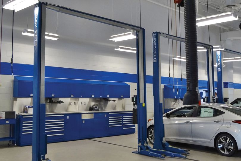Service bay with blue vehicle lifts and matching blue workbenches and tool storage