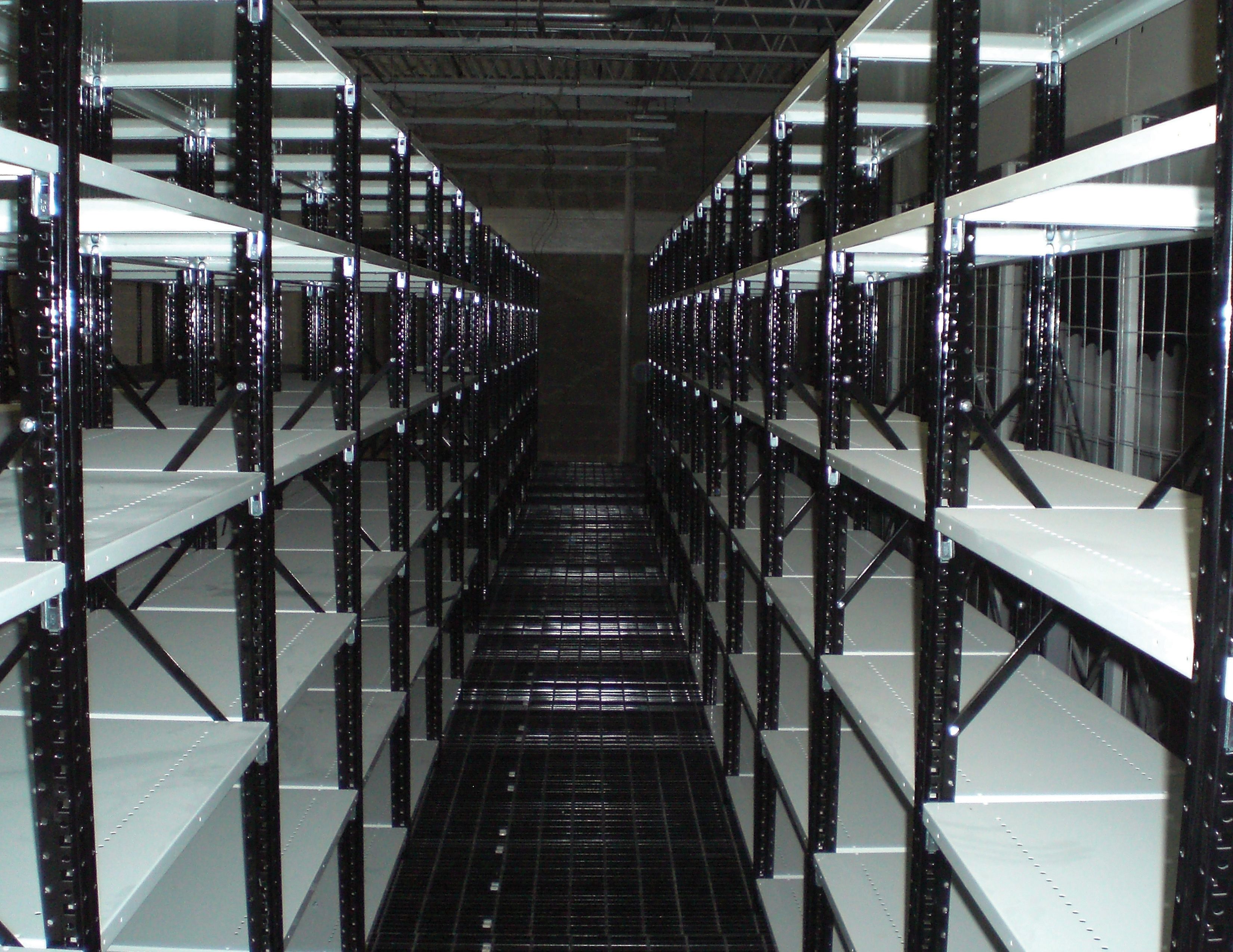 Long aisle of black steel shelving units in a parts storage room