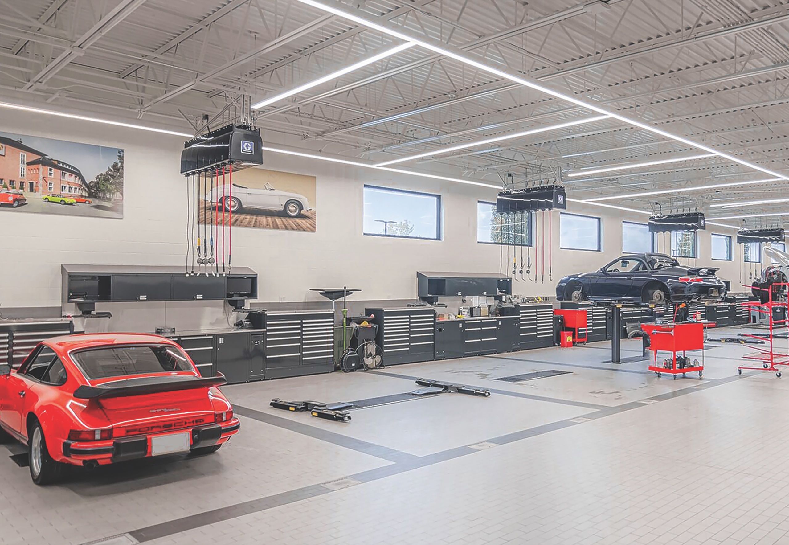 Bright service hall with a red classic sports car, red tool carts and black workbenches along the wall