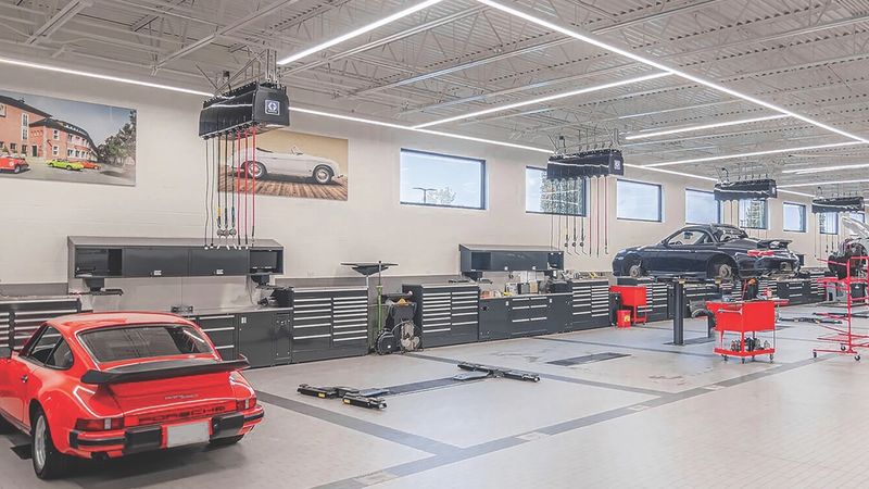 Bright service hall with a red classic sports car, red tool carts and black workbenches along the wall