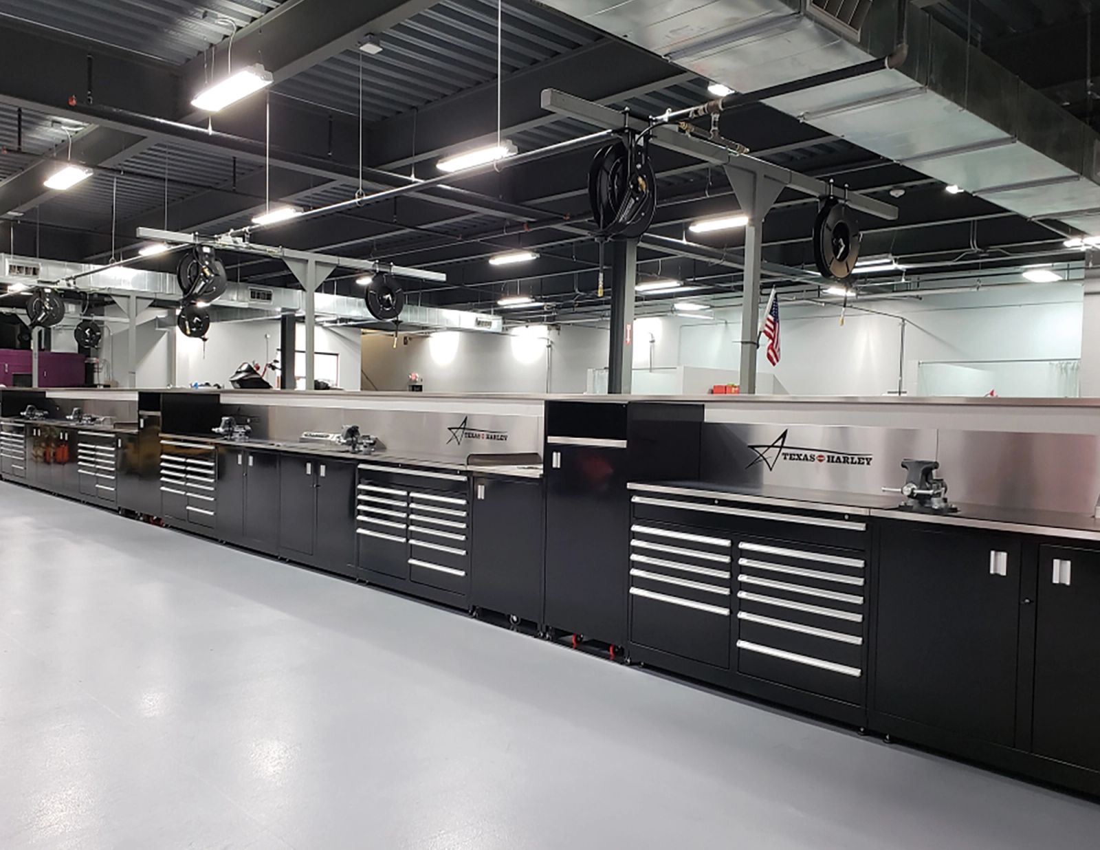 Long run of black steel cabinets and stainless-steel workbench tops in a clean service shop