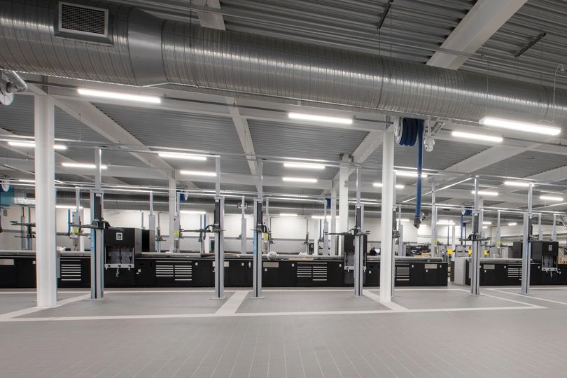 Large service hall with vehicle lifts and black workbench systems along the back wall