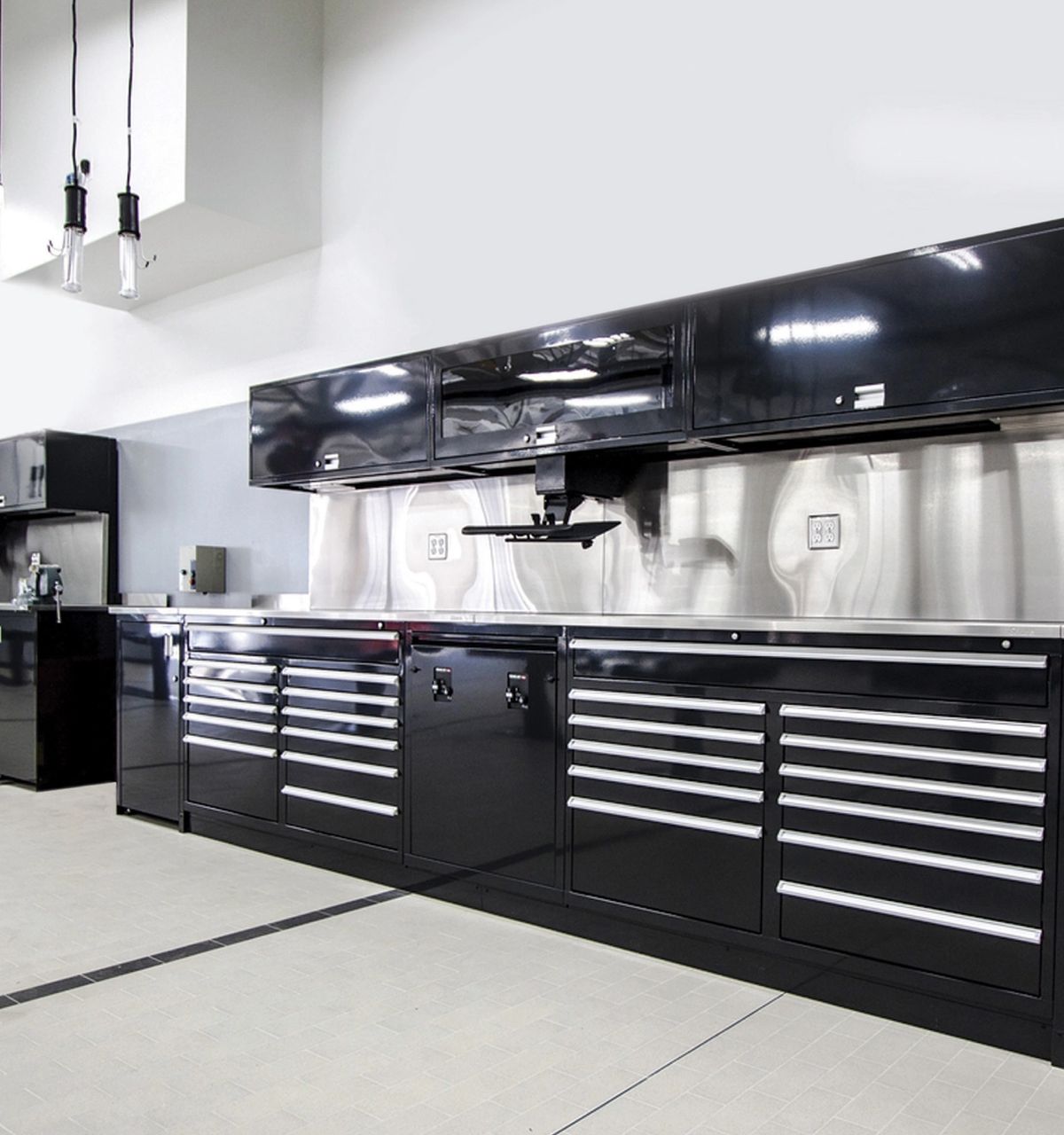 Black powder-coated workbenches with drawers and glossy black upper cabinets in a modern shop