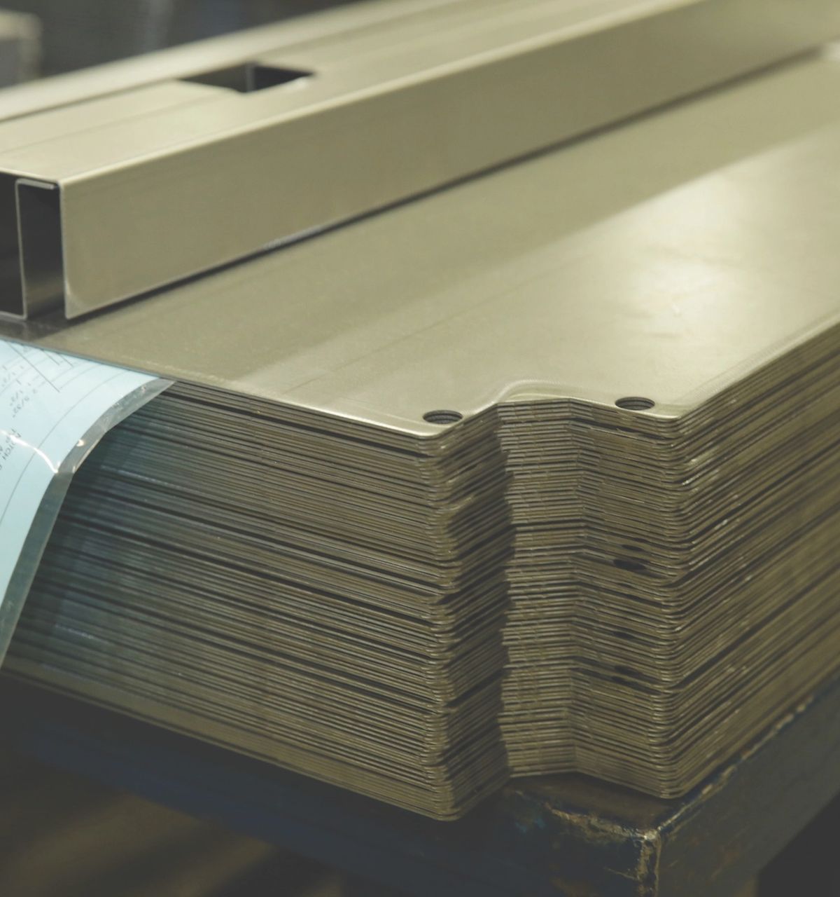 Stack of formed sheet-steel parts with a Shure shop drawing on top