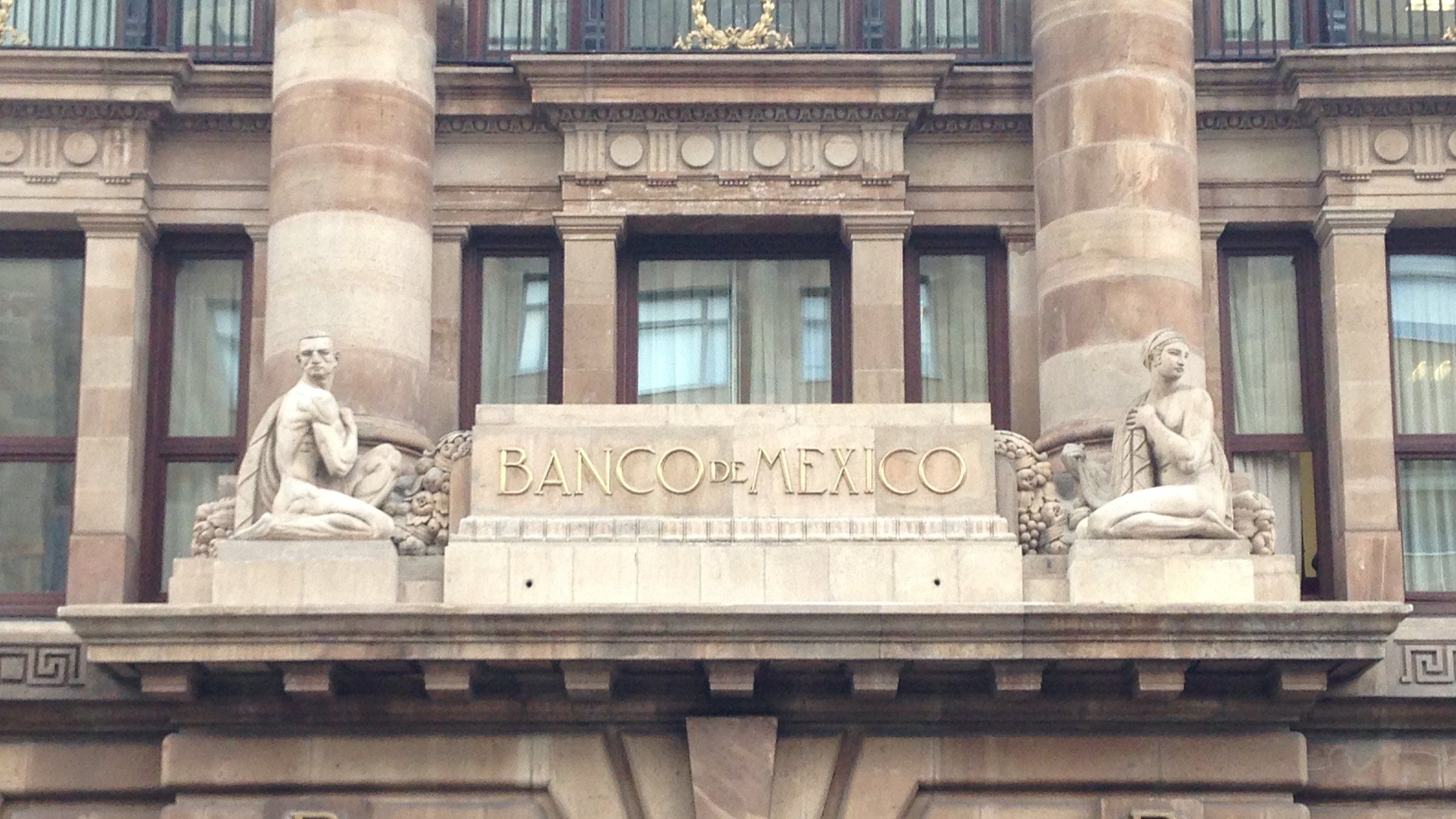 Fachada de cantera del edificio del Banco de México en el Centro Histórico de la Ciudad de México, con la inscripción «Banco de México» entre dos esculturas sobre la puerta principal.