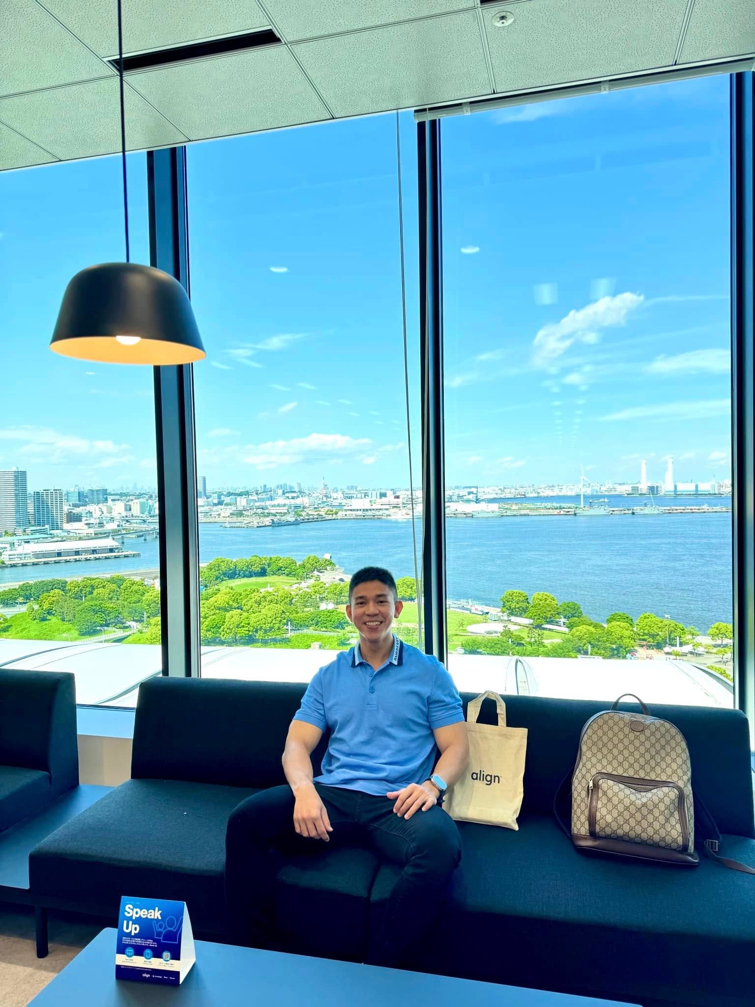 Bác sĩ Hồ Lê Bảo Ân ngồi tại khu chờ của văn phòng Align Technology, phía sau là khung cửa kính nhìn ra khu vực cảng.
